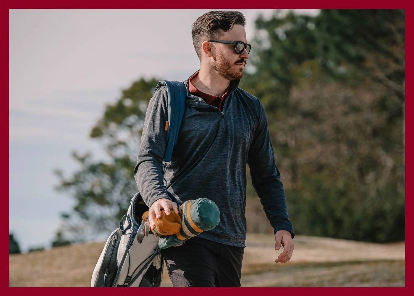 Male model wearin ggrey polo and grey pants, holding a putter on a green.