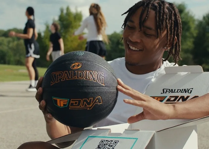 Man holding TF DNA Smart Basketball and phone looking at the TF DNA App