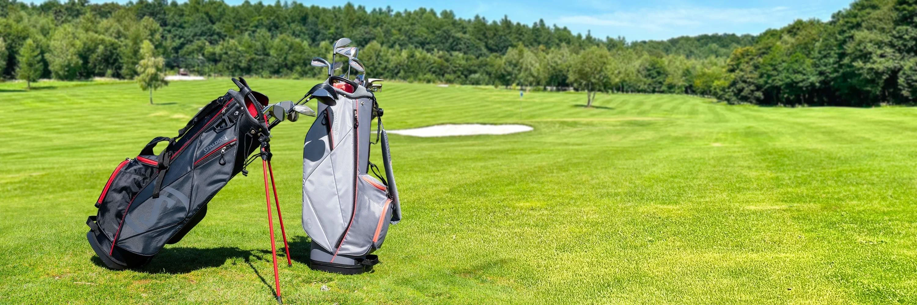 Golf bags positioned on a fairway of a golf course under an open sky.