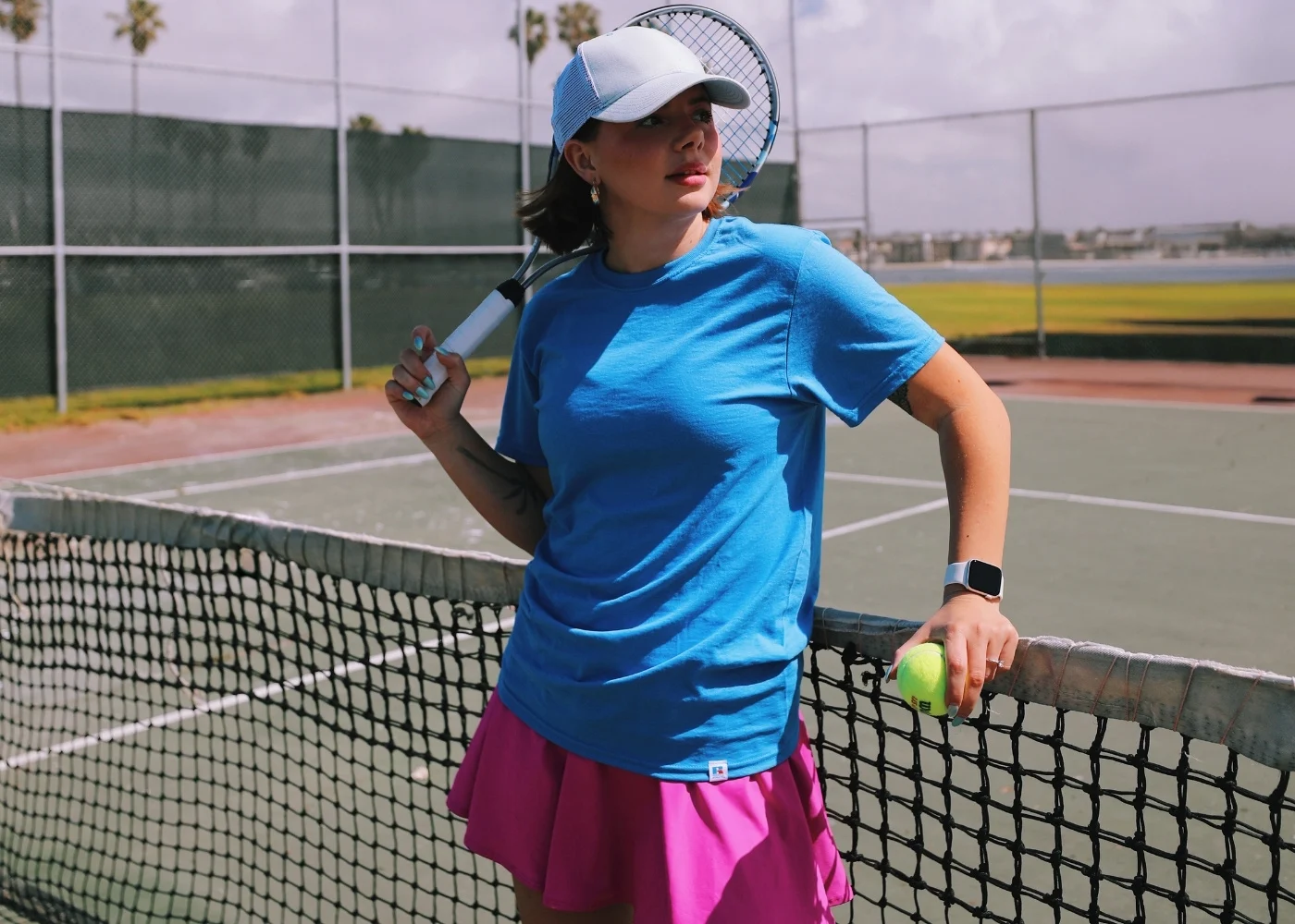 Female model wearing blue russell athletic performance top holding a tennis racket