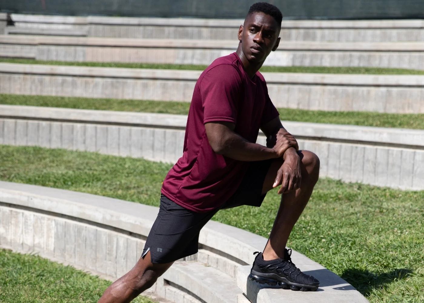 Male model wearing grey russell athletic performance shorts and burgundy athletic shirt