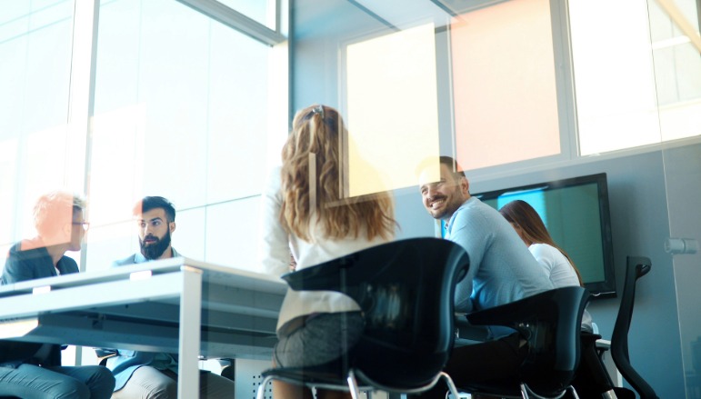 Colleagues in a meeting room, smiling.