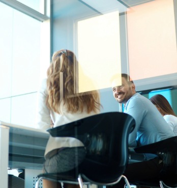Colleagues in a meeting room, smiling.