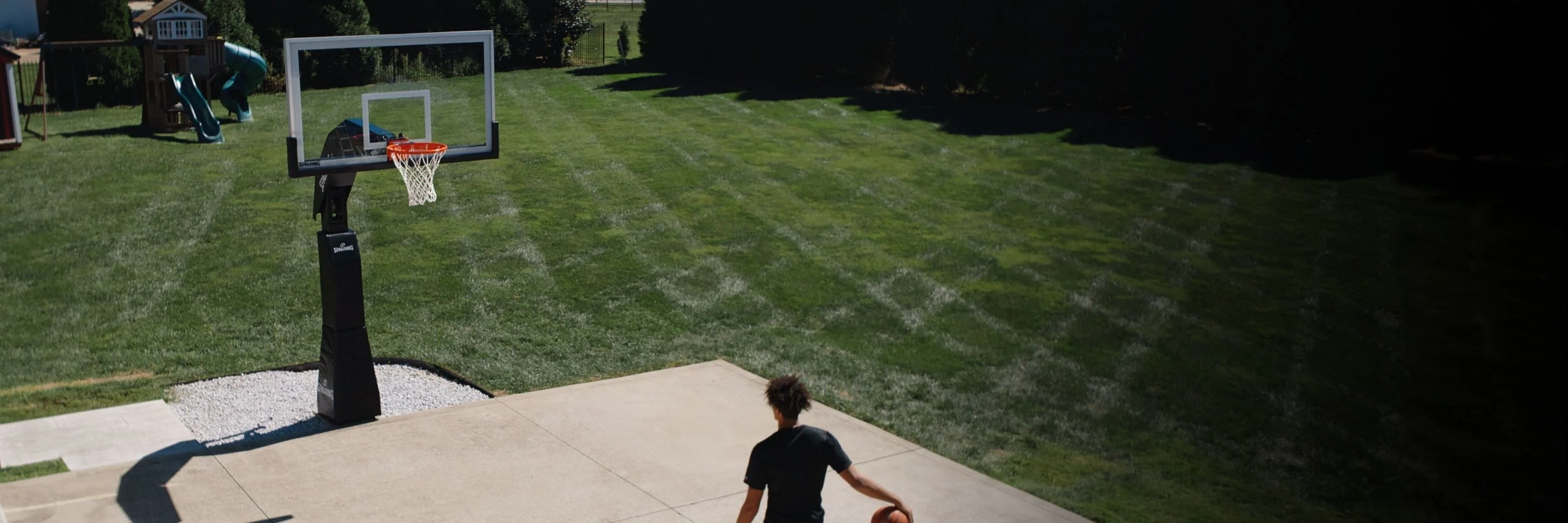 Four Spalding basketballs, including Rookie Gear, Marble Series, and Excel TF-500 models, displayed on an outdoor asphalt basketball court.
