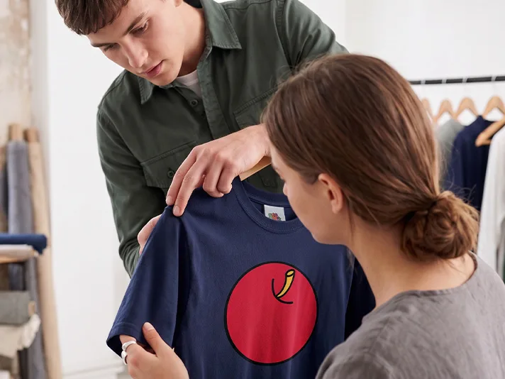A young man and woman are embroidering one of our T-shirts.