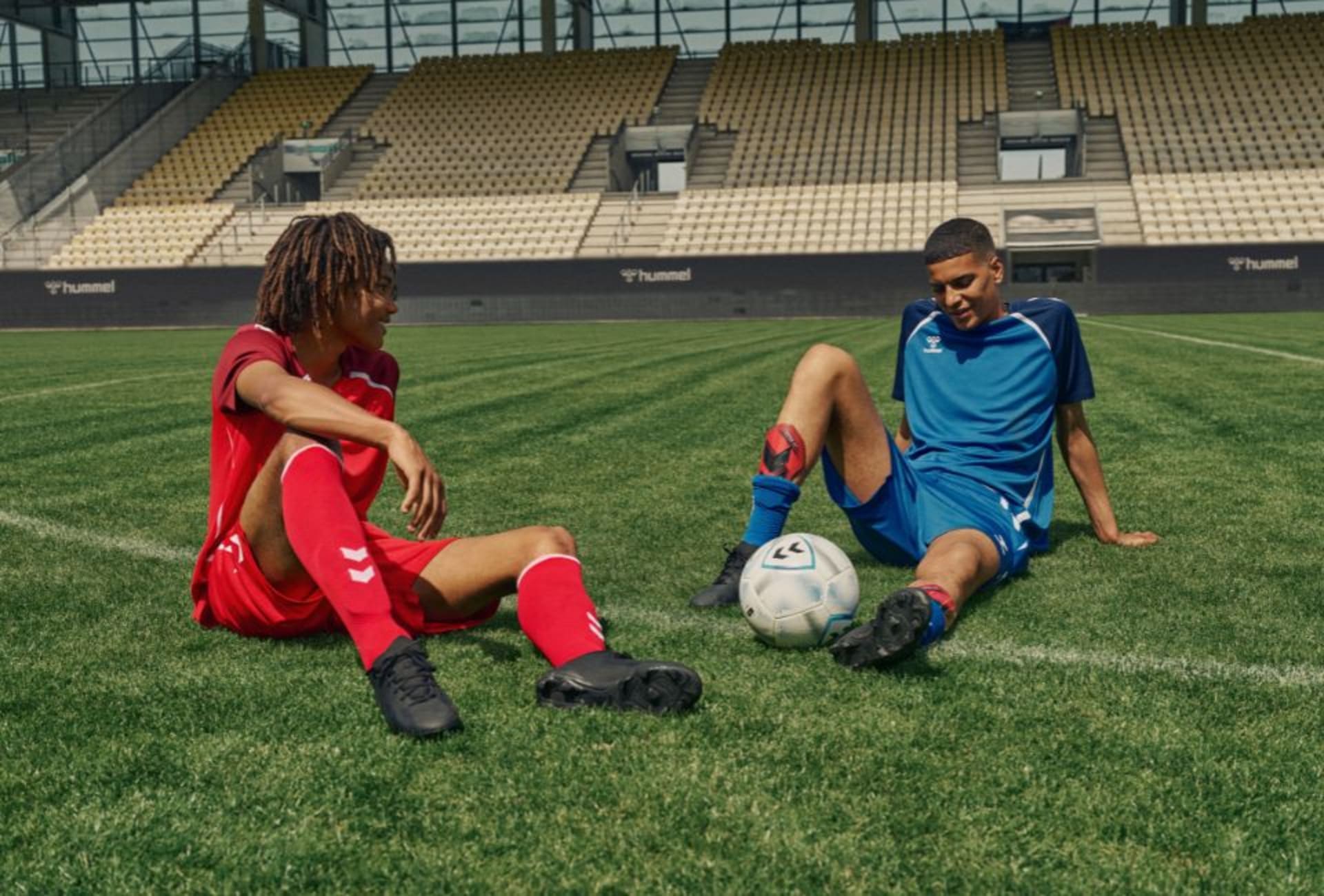 Zwei Fussballspieler sitzen auf dem Rasen.