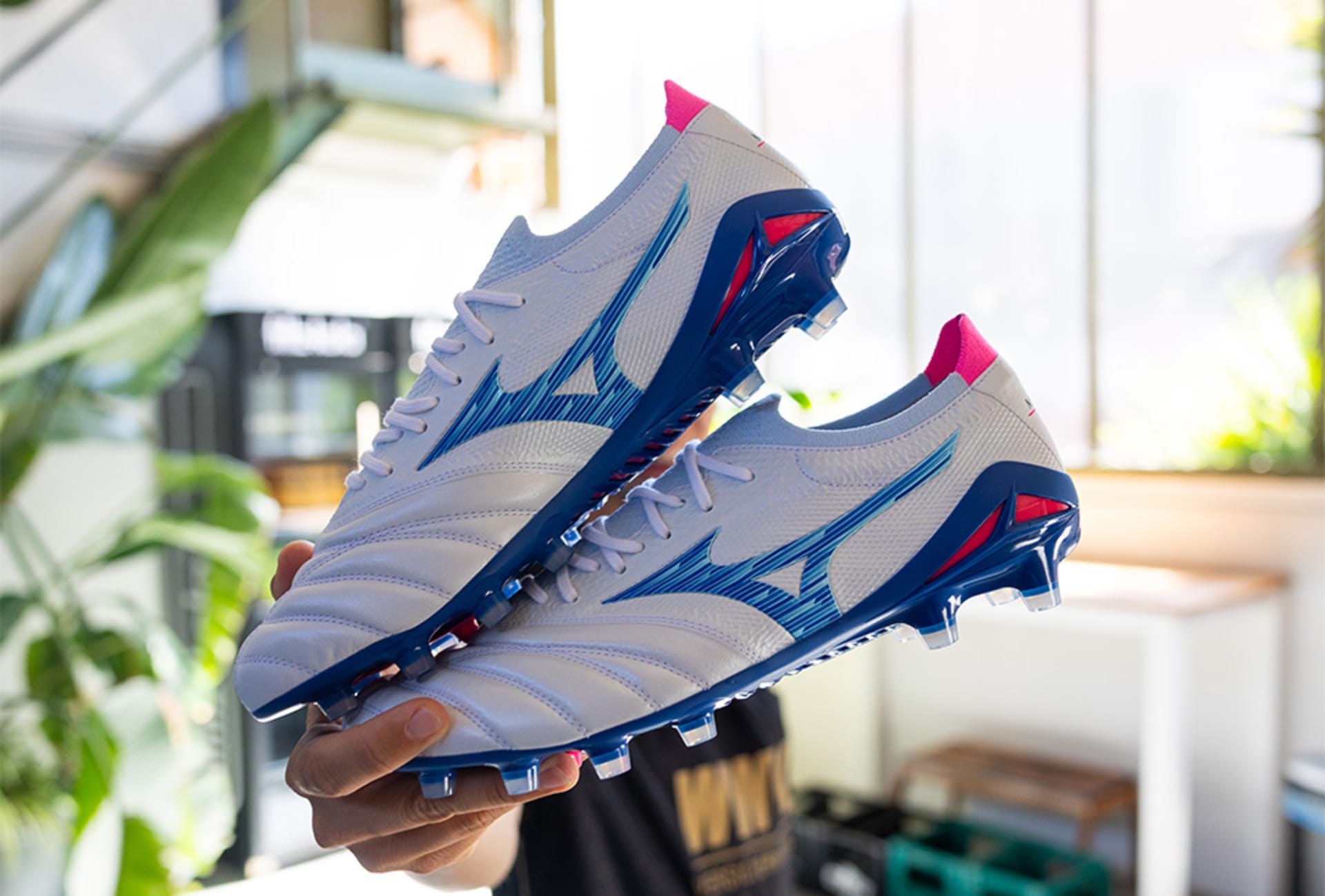 Ein Paar Mizuno Urban Electric Fussballschuhe werden in der Hand gehalten.