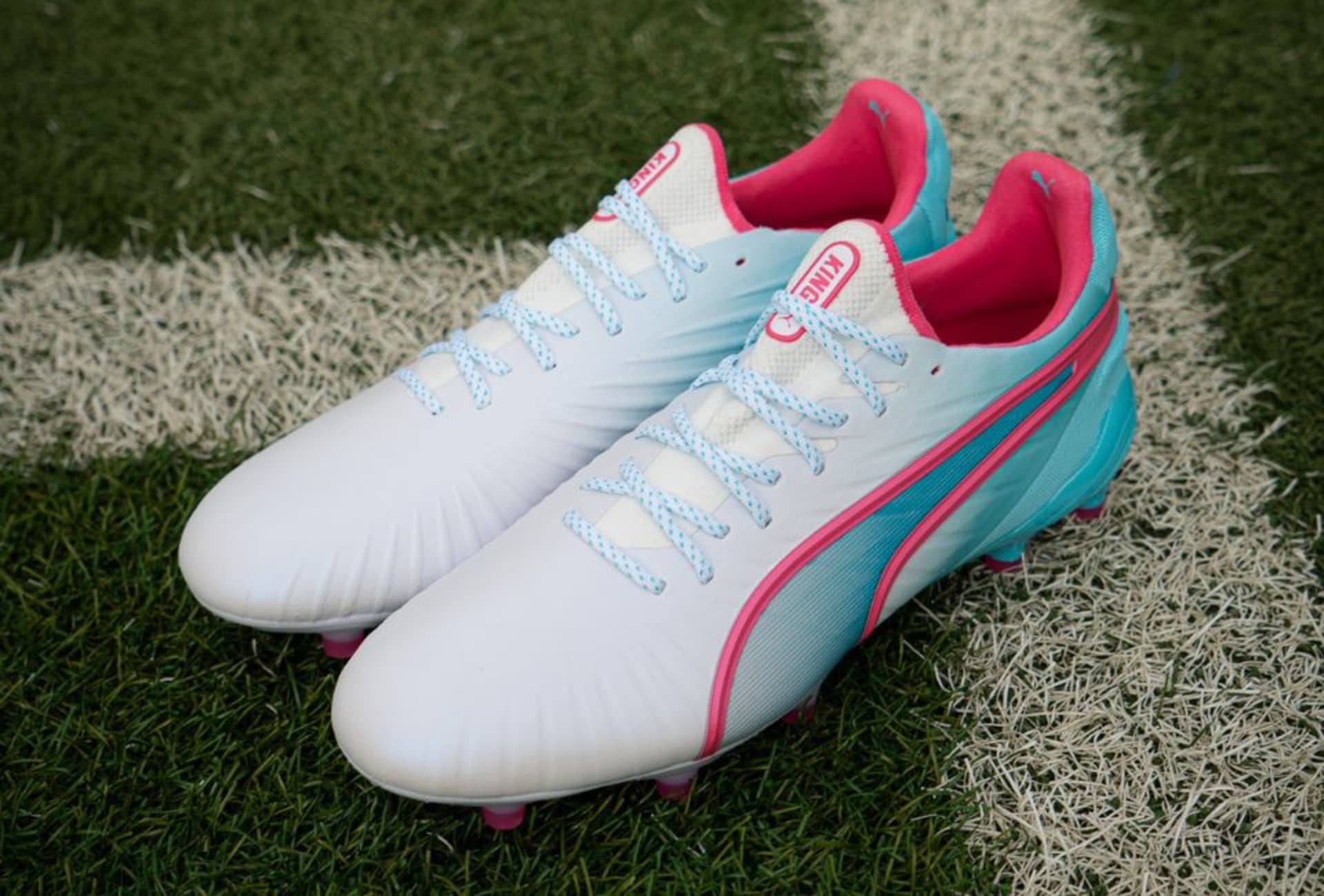 Ein Paar Puma Re-Charge Fussballschuhe stehen auf dem Rasenplatz.