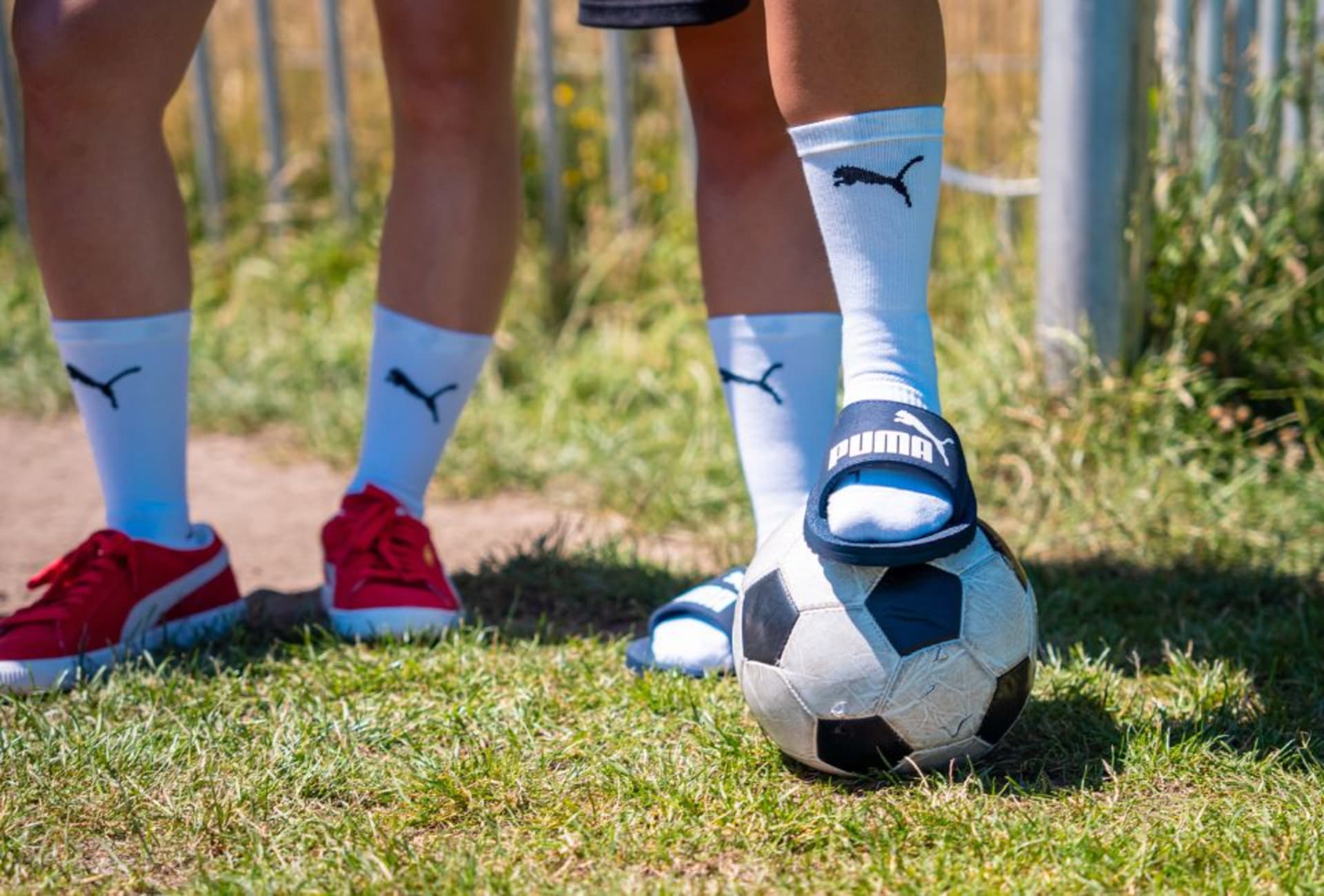 A Coral Blaze adidas football boot is held up to the camera.