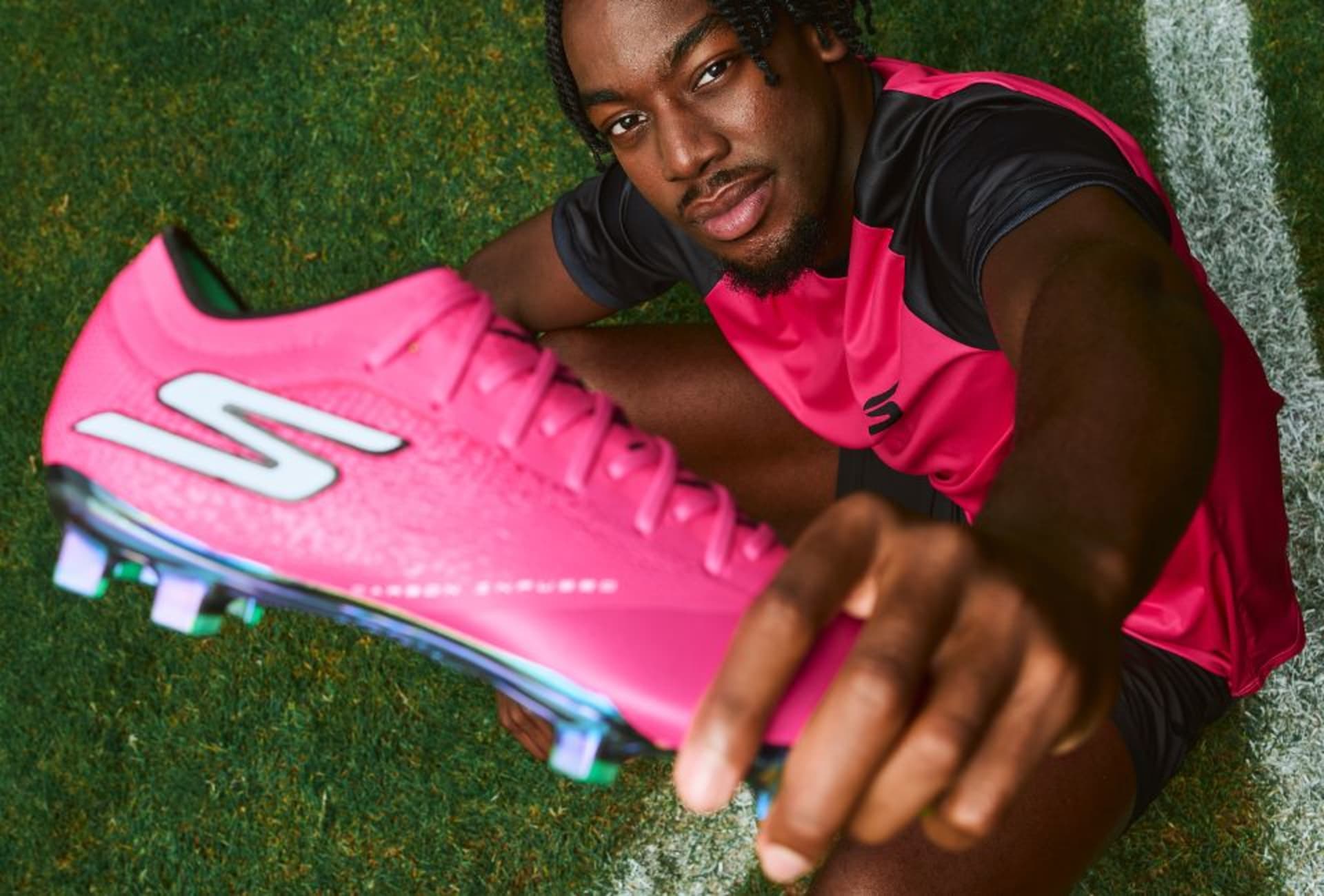 Three adidas Coral Blaze Pack football boots on the grass.
