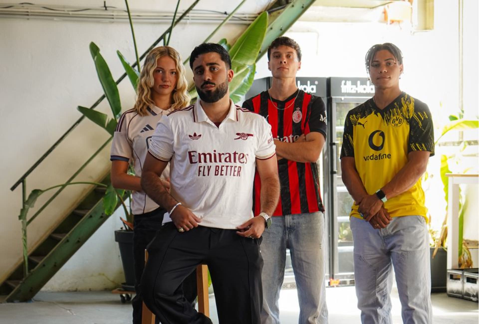 Models tragen Fußballtrikots in einem modernen, urbanen Setting – sportlich und stilbewusst.