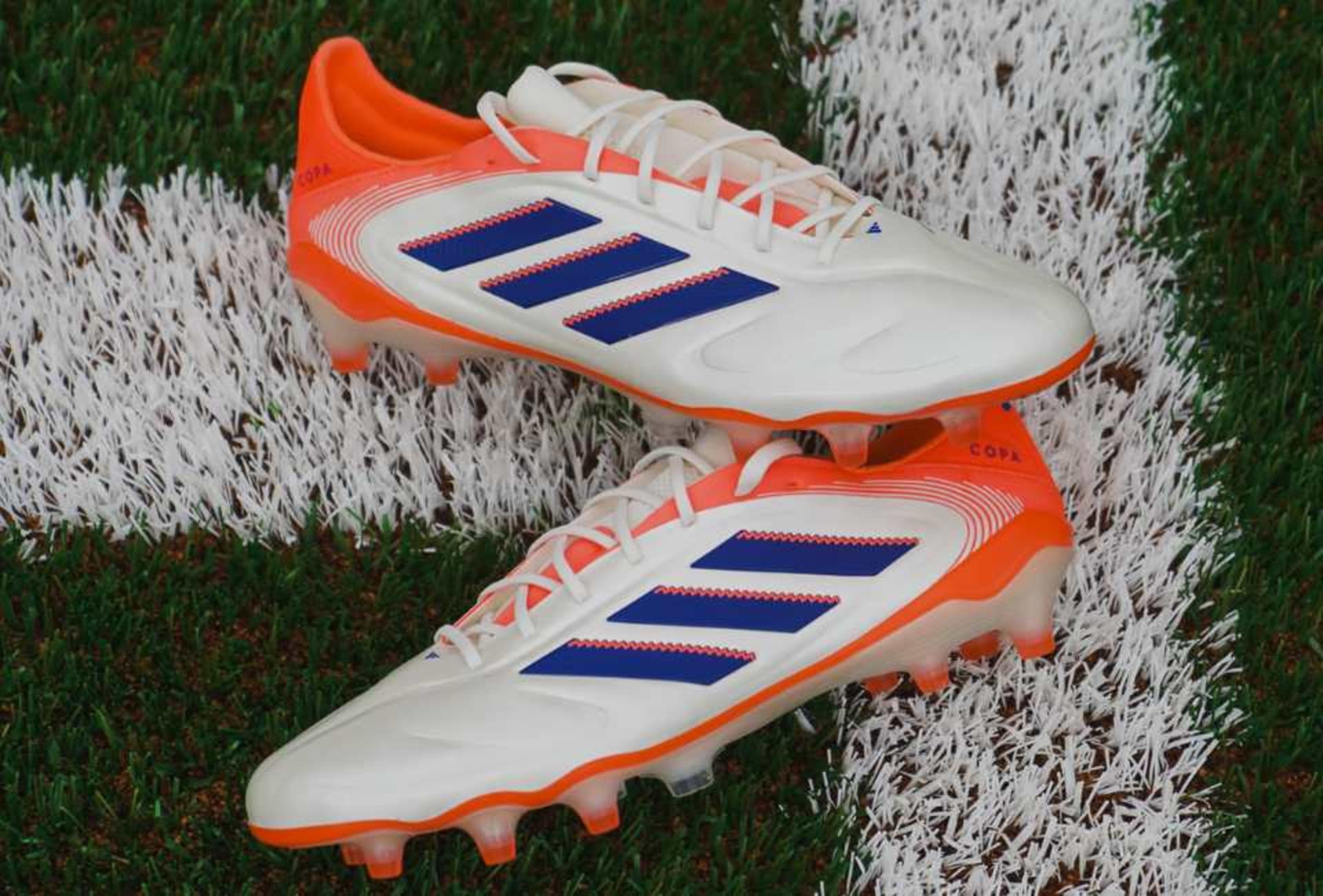 Ein Paar adidas Coral Blaze Pack Fussballschuhe liegen auf dem Rasen.
