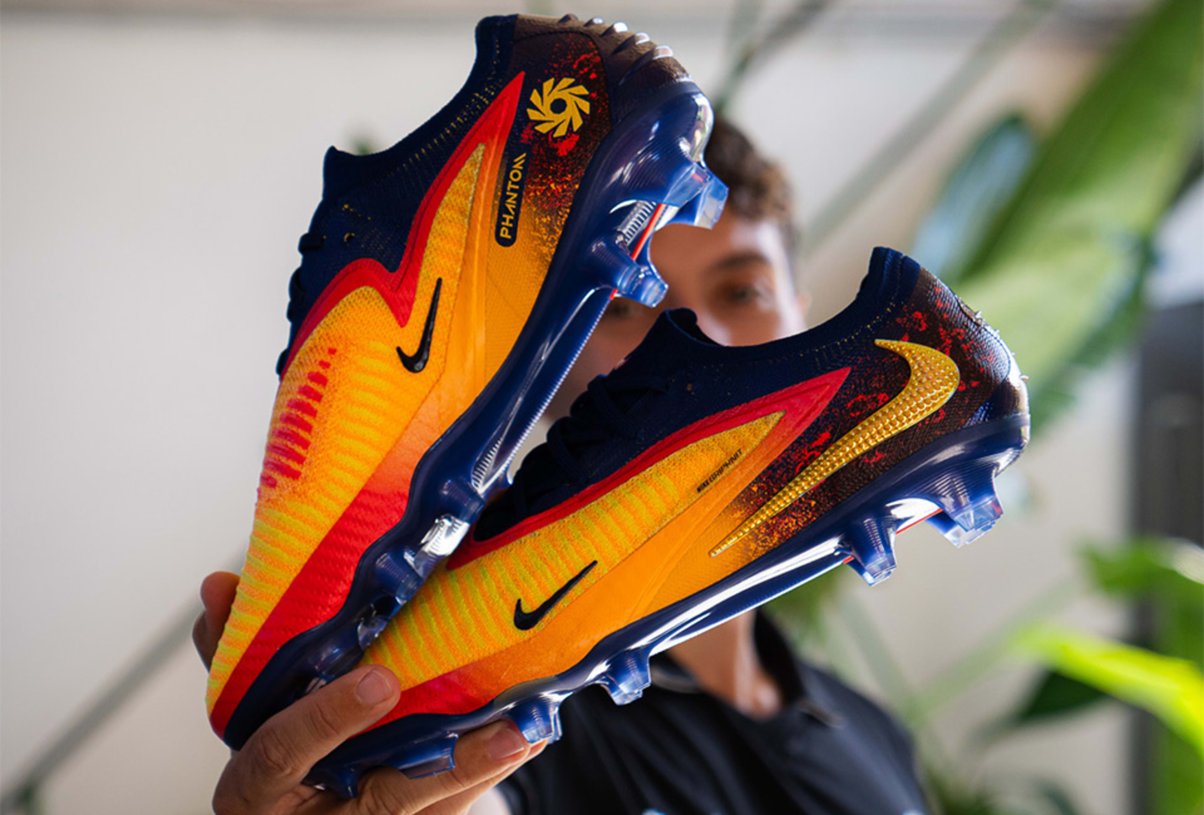 Ein paar Nike Haaland Phantom 6 Fussballschuhe werden in die Kamera gehalten.