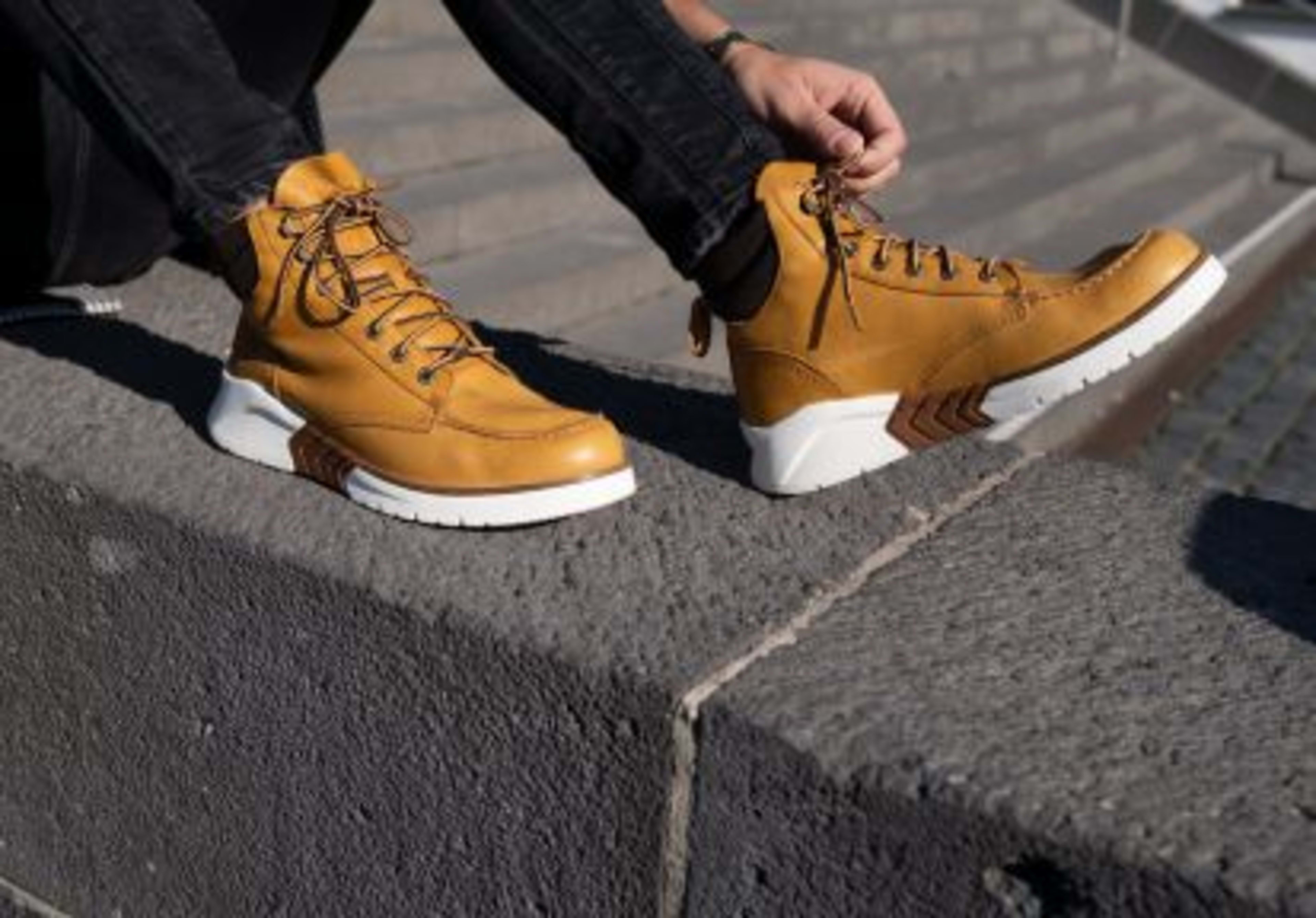 Mann traegt braune Timberbland Schnuerschuhe am Fuss.