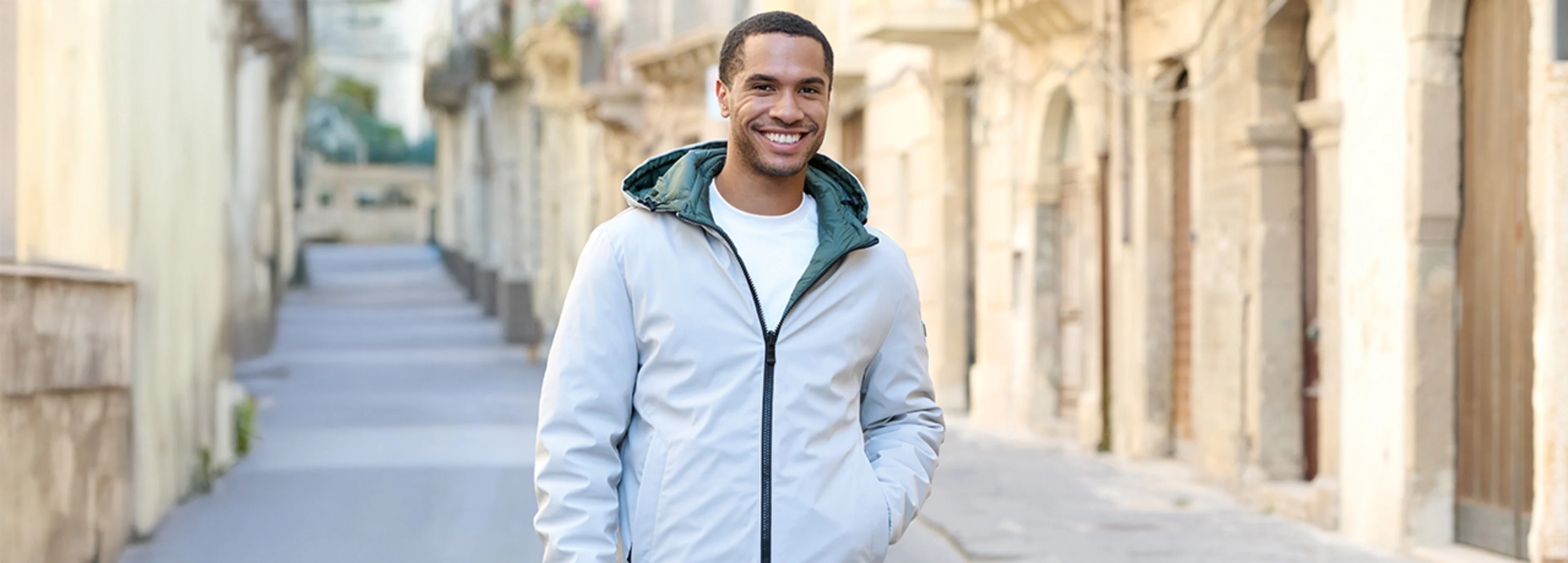 Stylische Wendejacke für Herren in Grün und Silbergrau, kombiniert mit einem weißen Basic T-Shirt und einer Jeans.