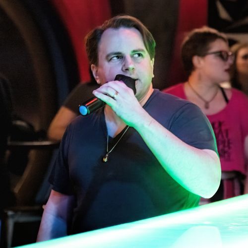 Derek Houck holding a microphone while singing karaoke.