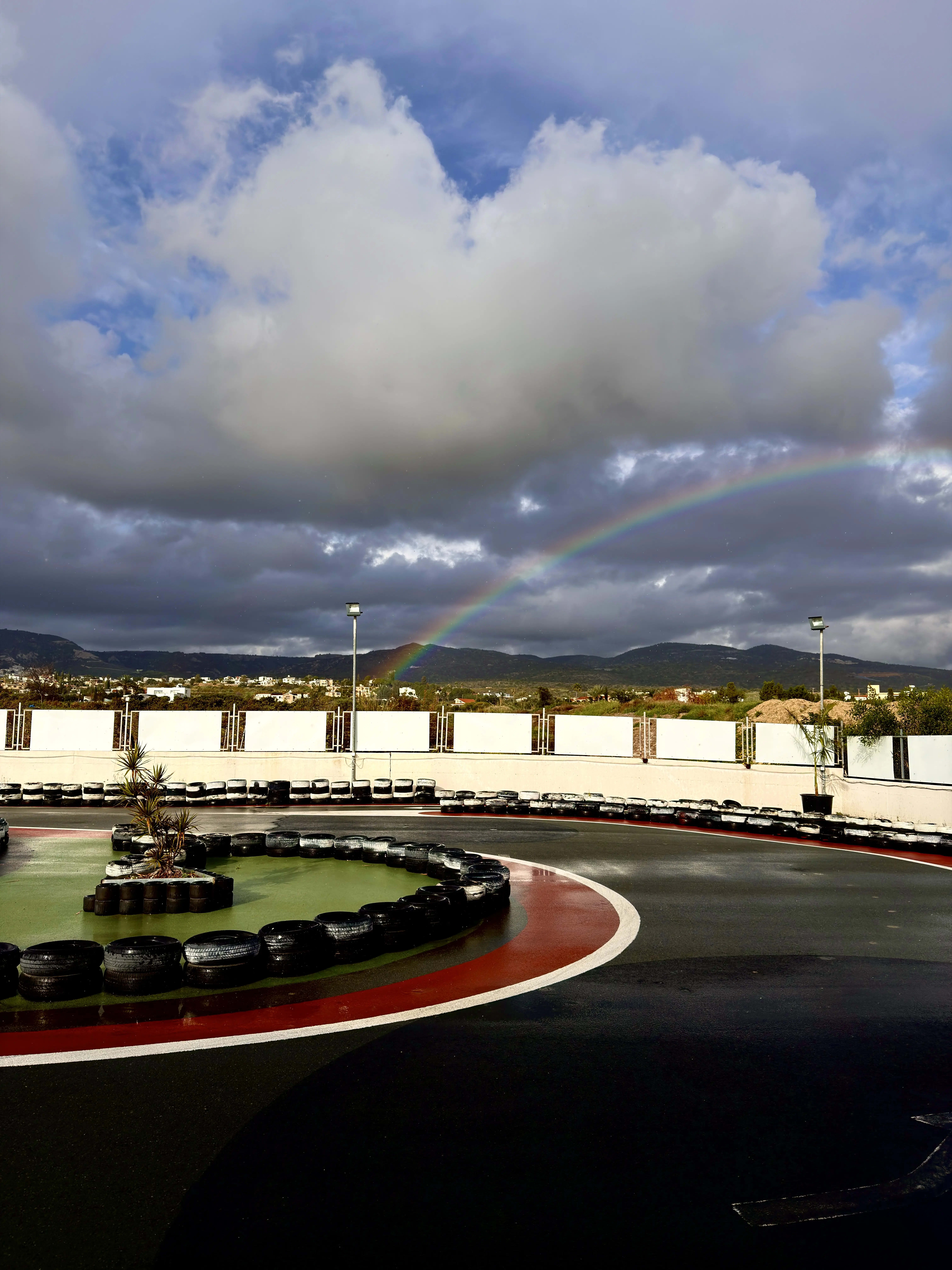 Wet kart track with reflections and rainbow in the sky