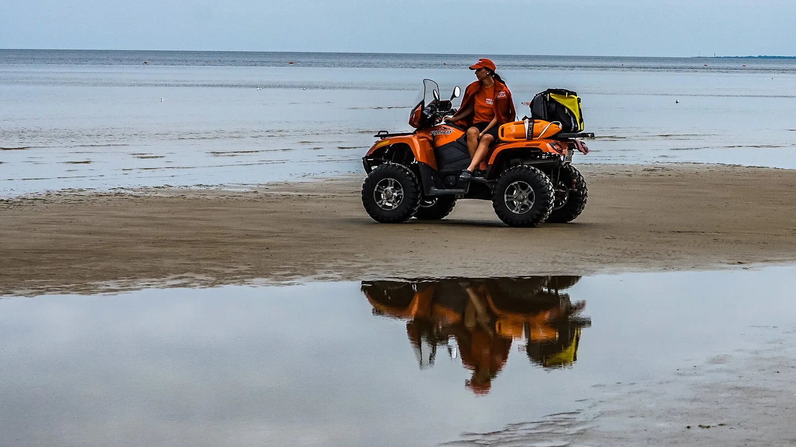 Quad bike rider on a wide wet sandy beach
