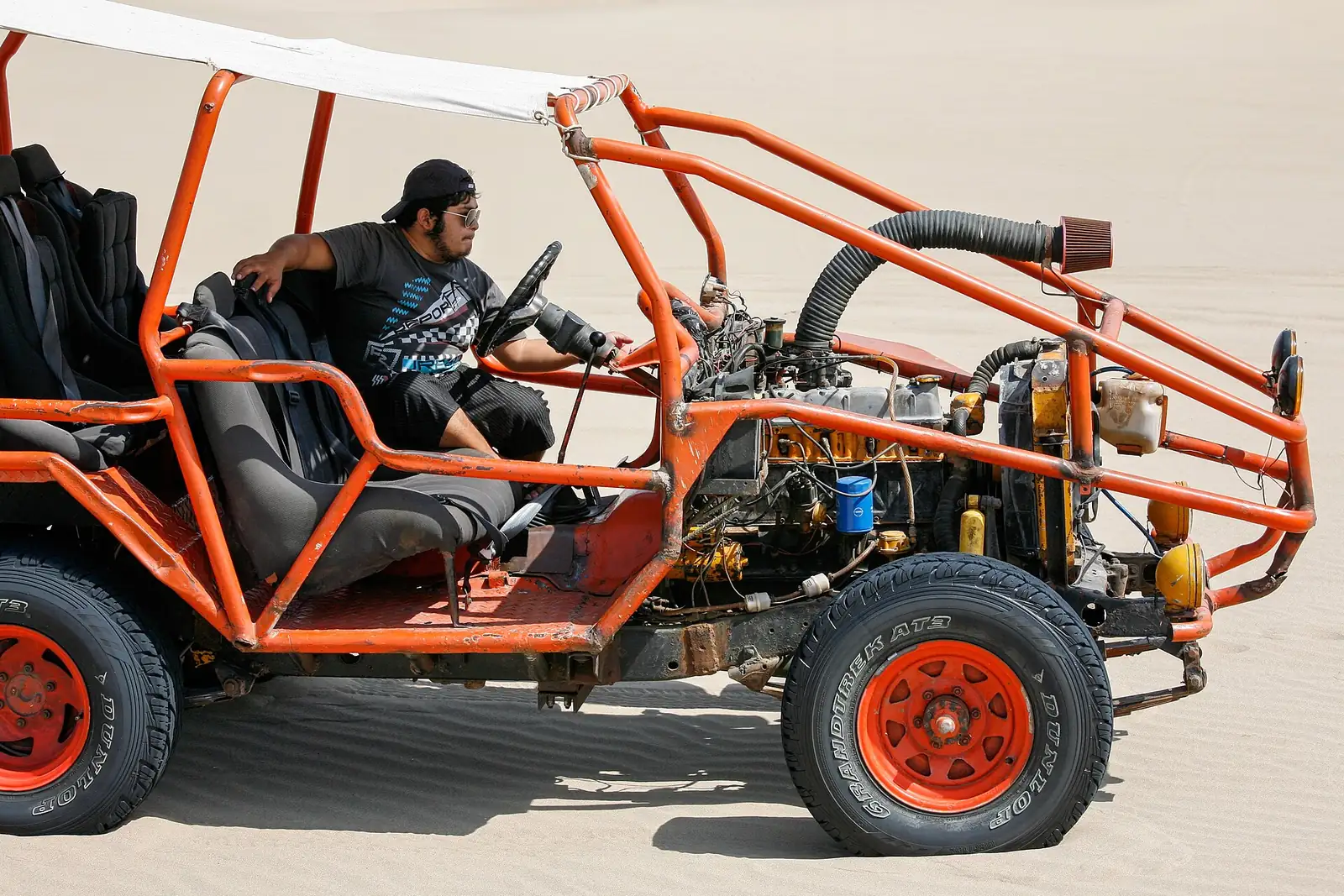 A dune buggy with roll cage parked on desert sand