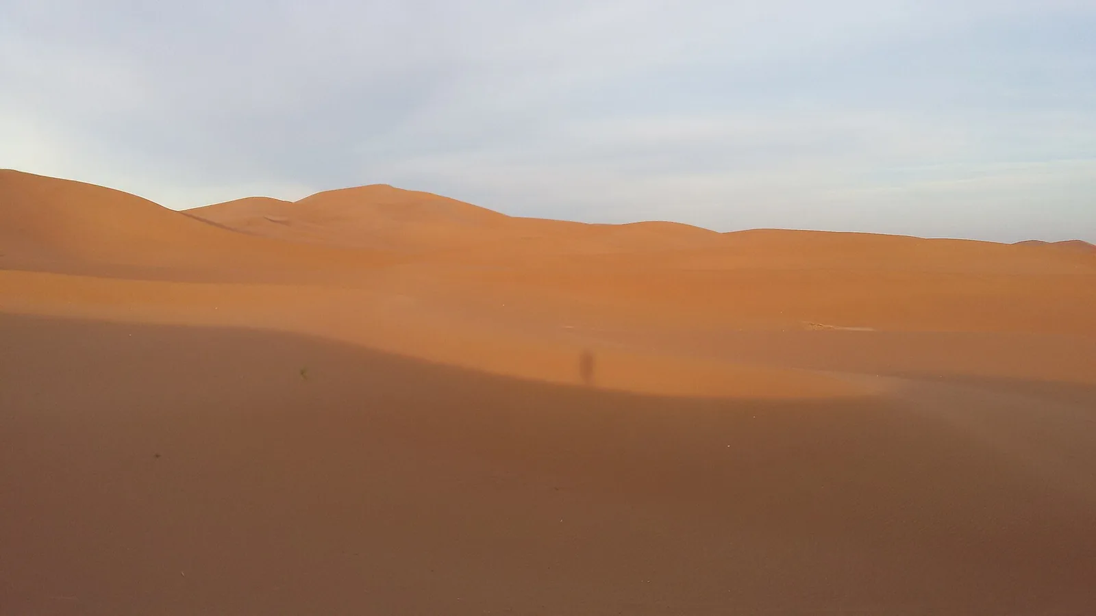 A walker’s shadow stretched across the sand at Erg Chigaga