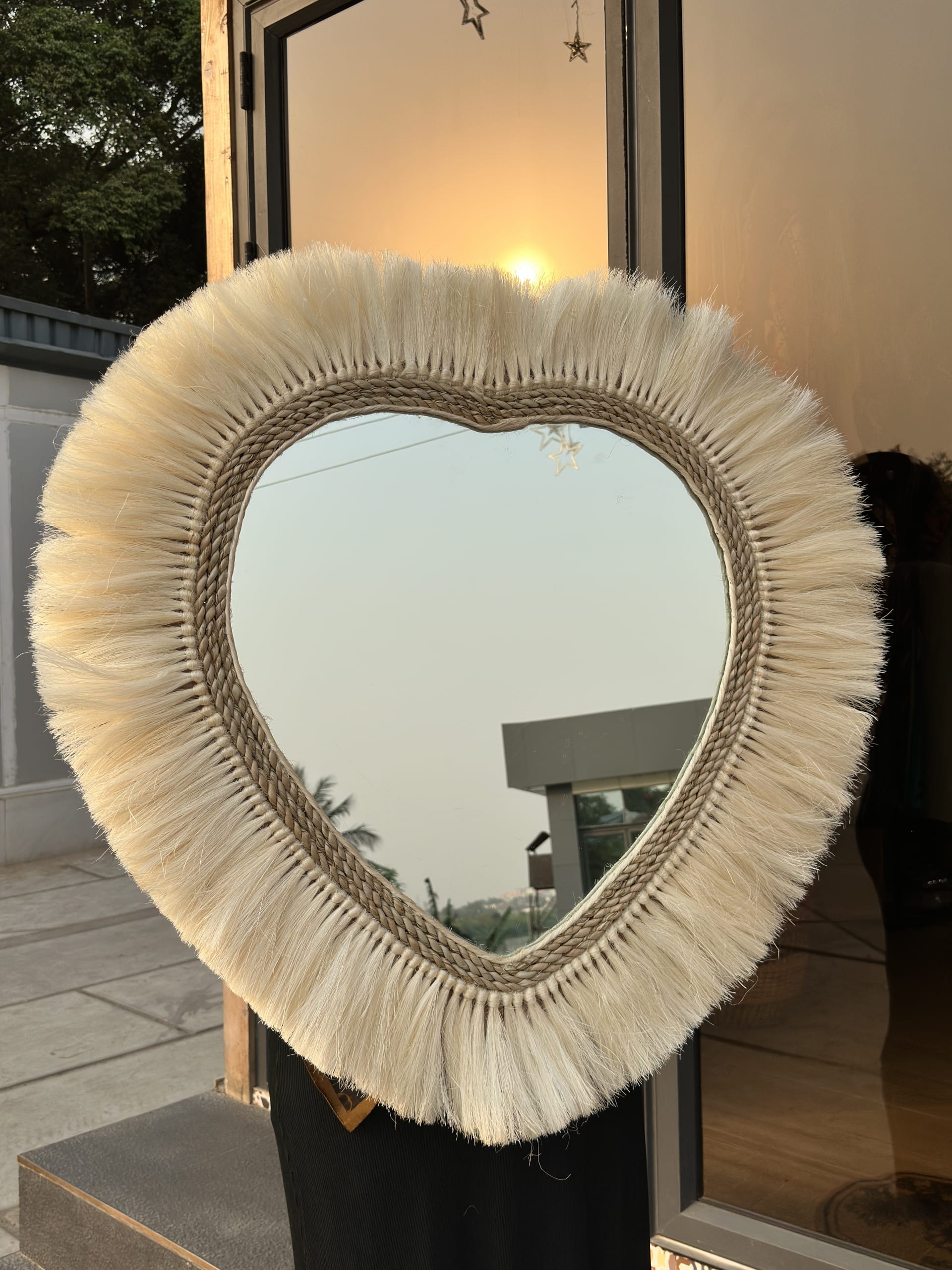 Boho-style heart-shaped wall mirror with macrame fringe.