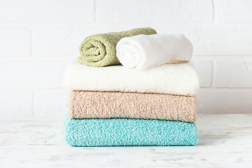 Stack of bath towels in white bathroom.