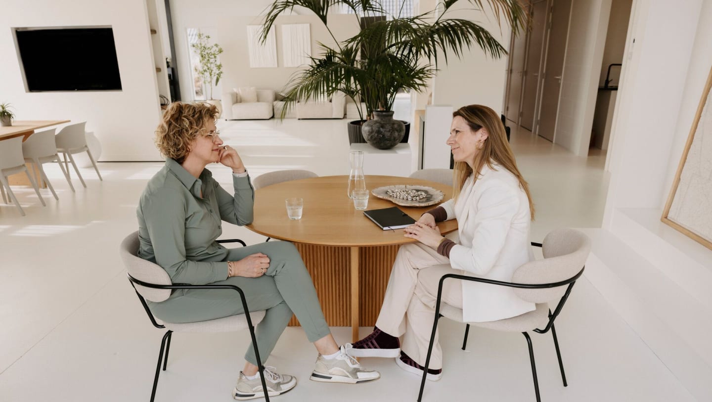 Coach en coachee in gesprek in sfeervolle ruimte