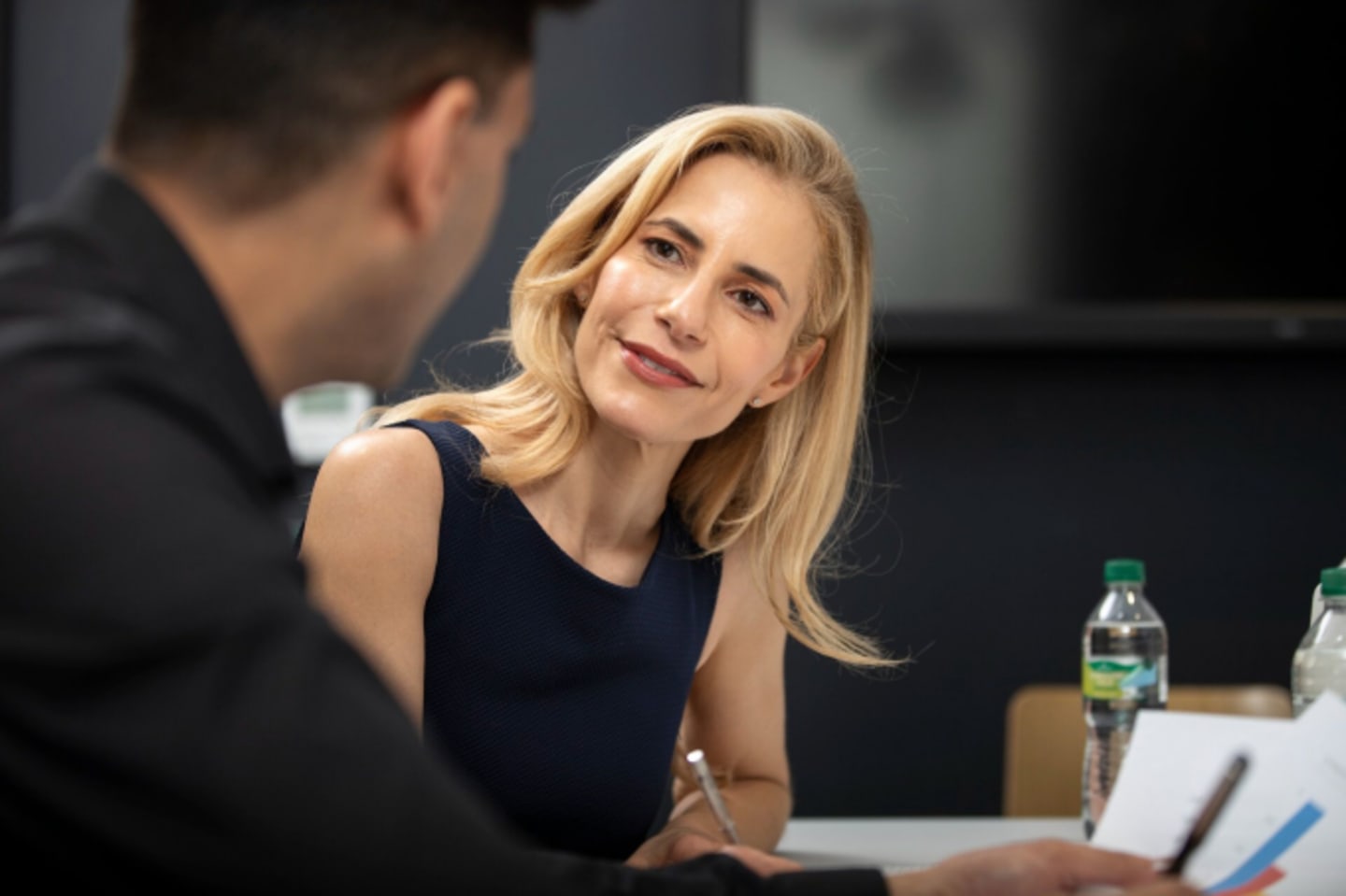 Blonde vrouw met ge-interesseerde blik luistert aandachtig naar gesprekspartner