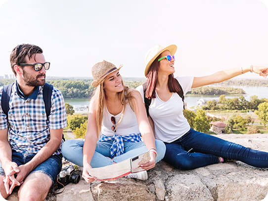 Travelers sitting outdoors with a map, enjoying the view