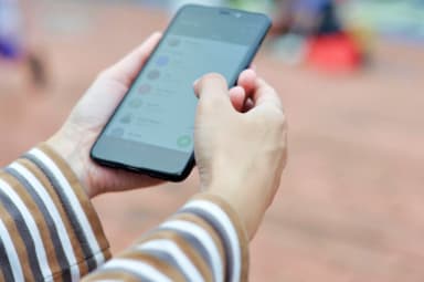 Close-up of hands holding a smartphone outdoors, browsing or navigating