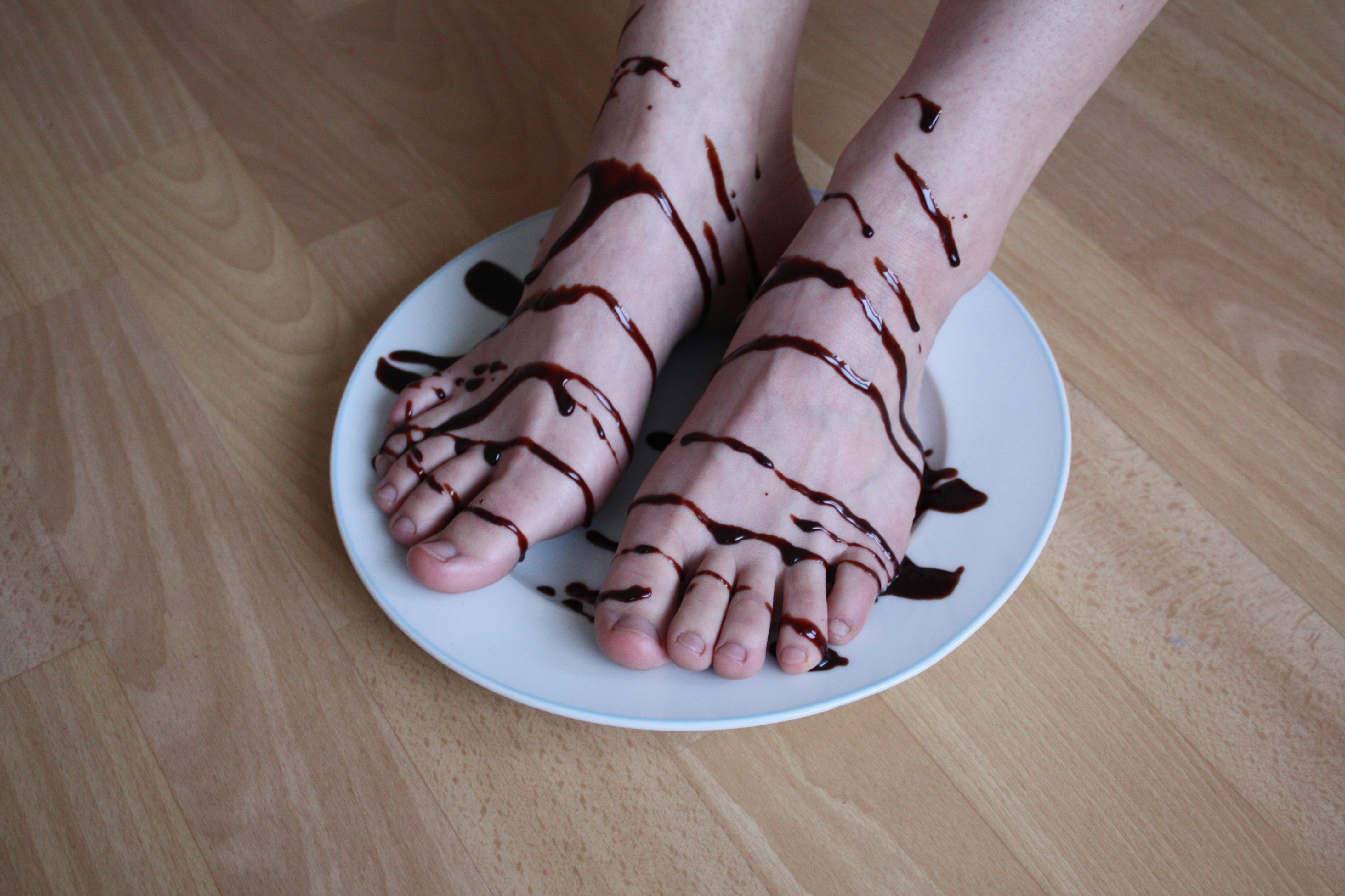 a woman's pale bare feet resting on a plate and decorated with chocolate sauce