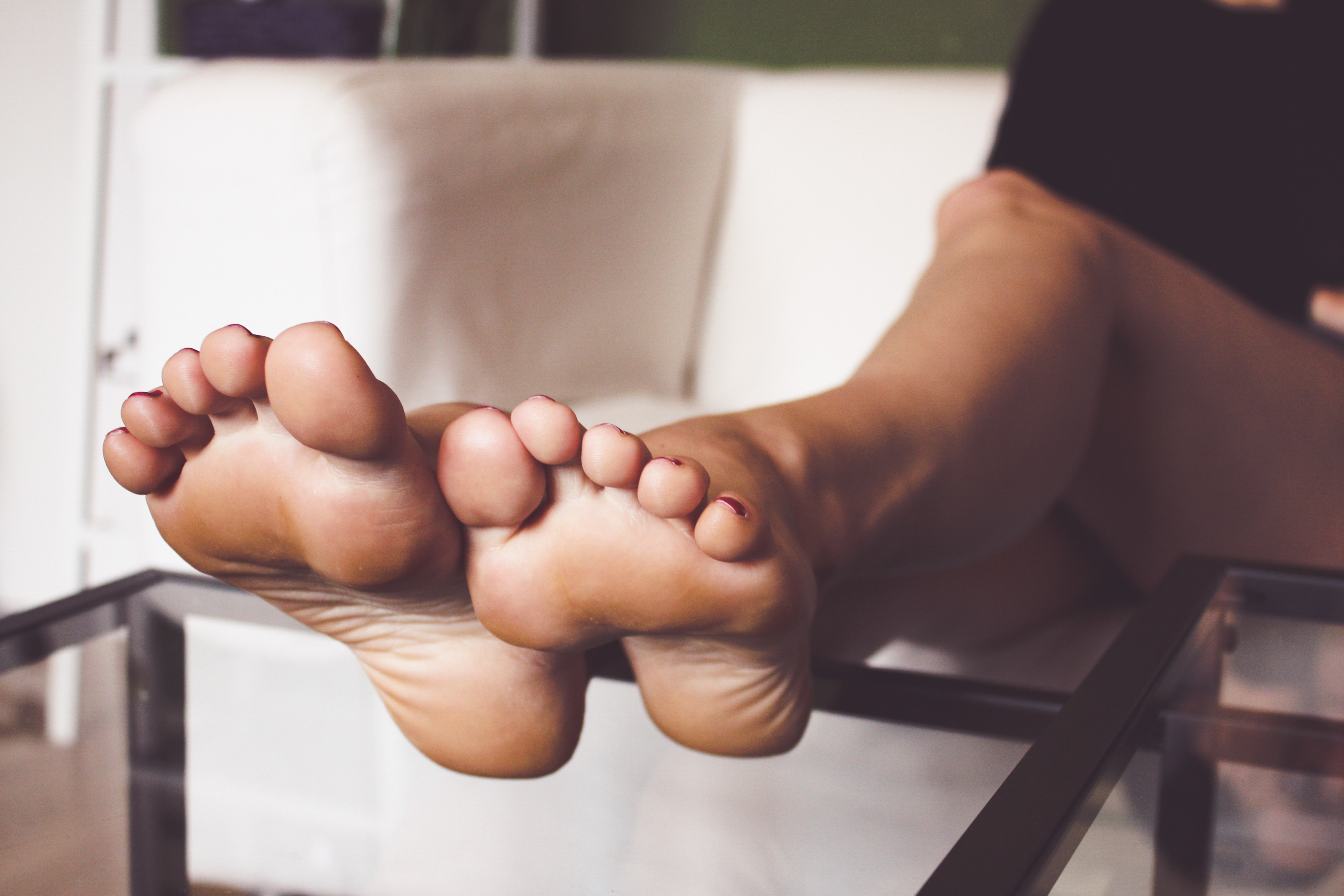 a woman's soles resting on a glass coffee table