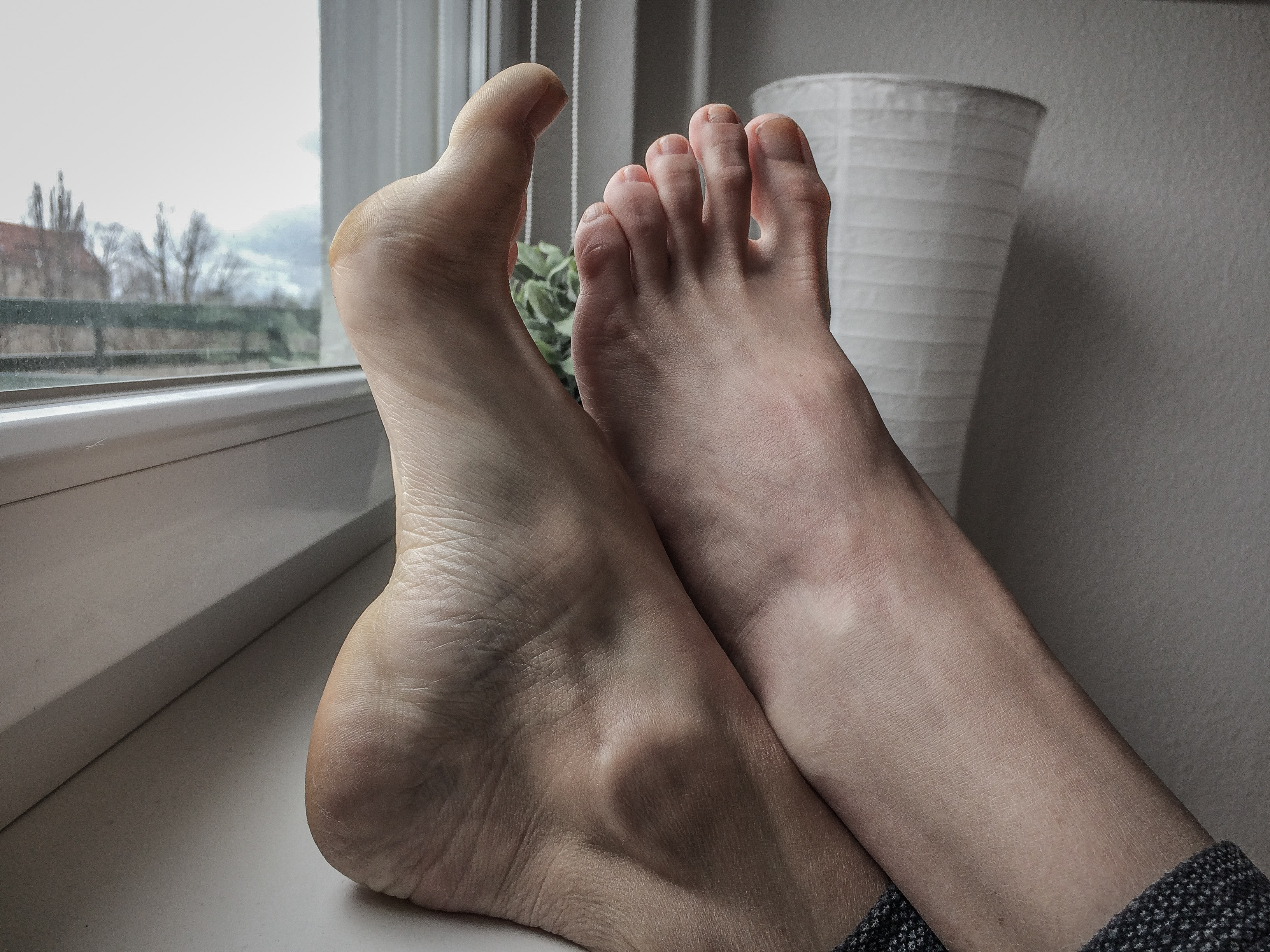 a woman's high-arched feet resting on a window sill