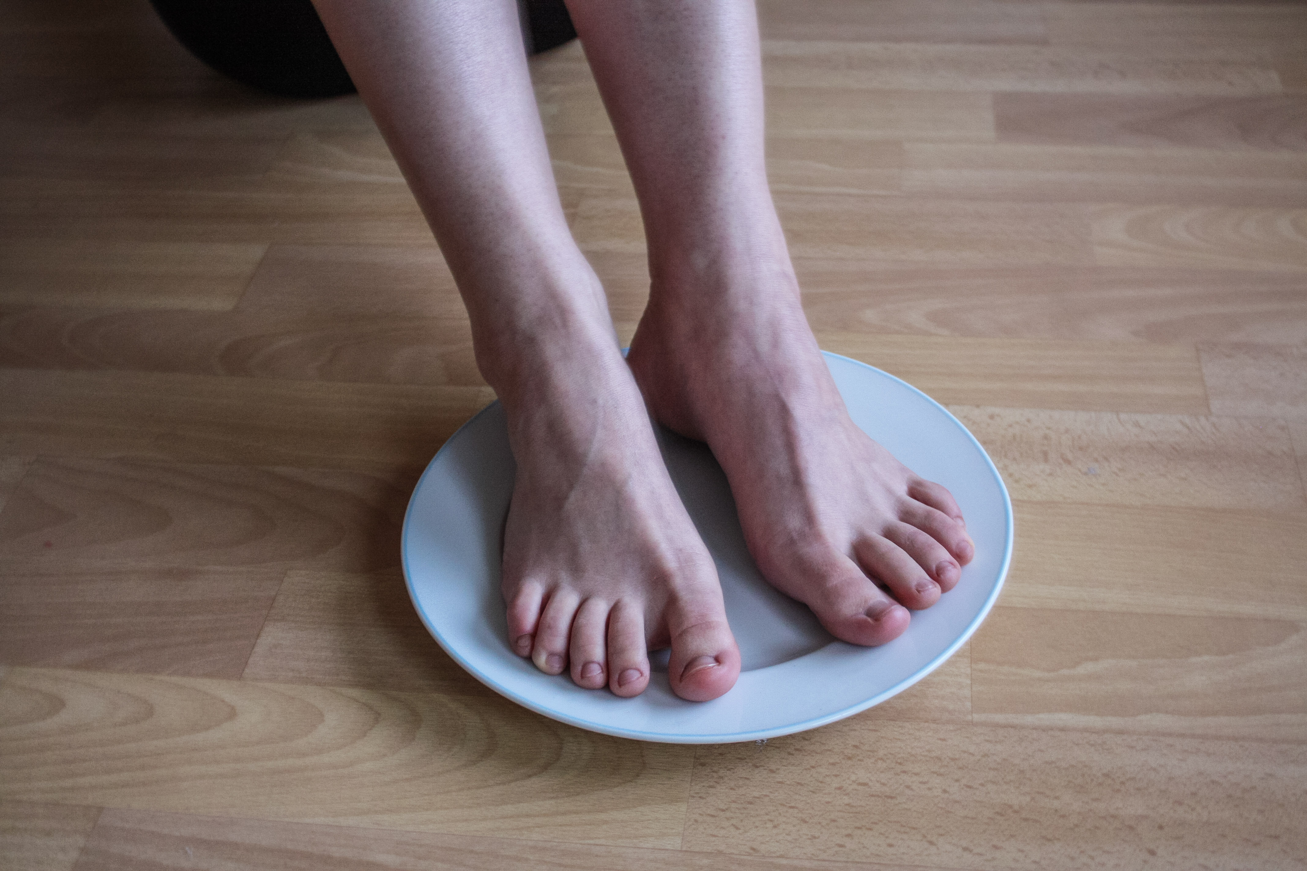 a woman's pale bare feet resting on a white plate