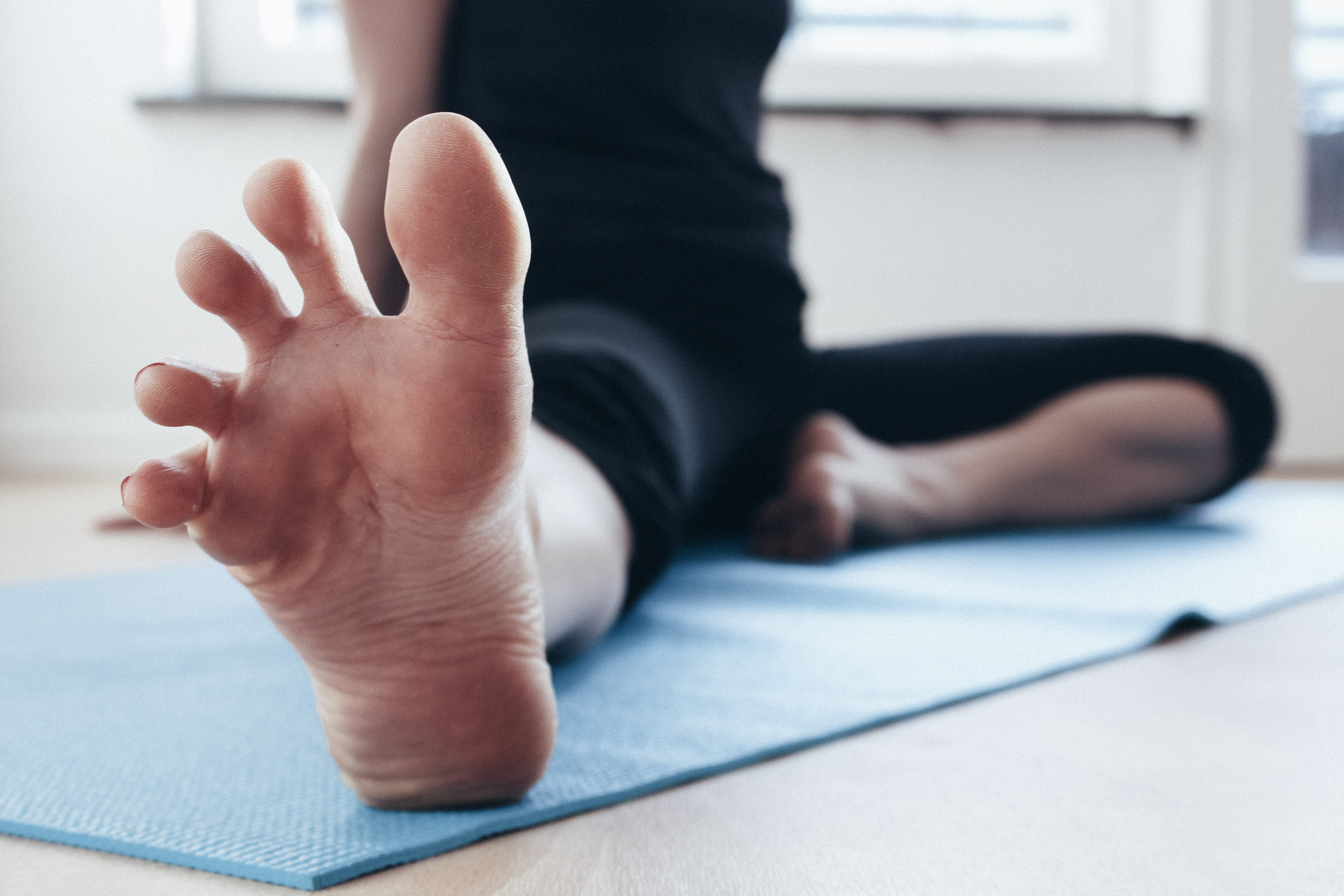 a woman sitting on a yoga mat with her toes spread at the camera