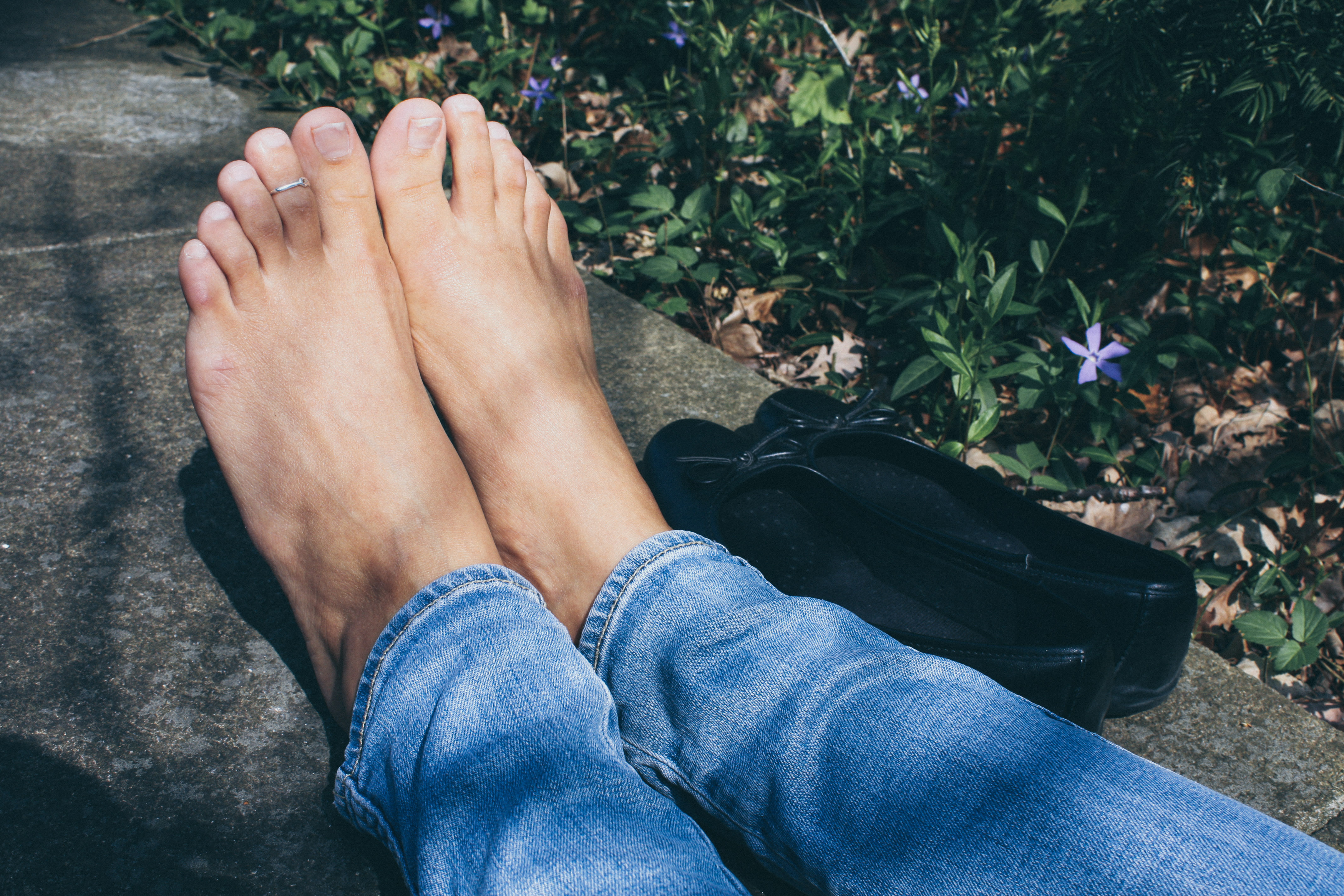 a woman's bare feet with her black ballet flats next to her feet