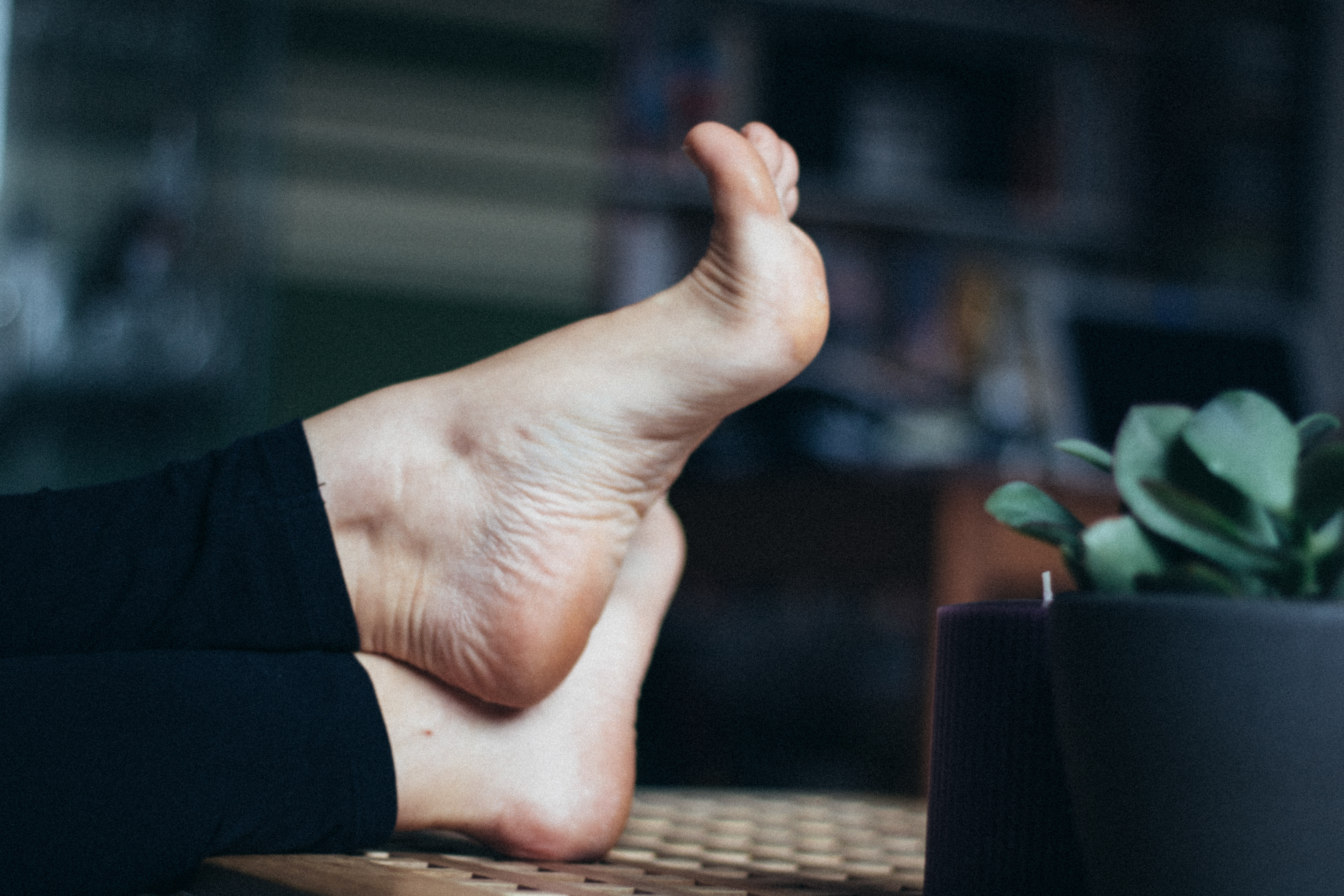 a woman's soles resting on a wooden coffee table with her arches flexed
