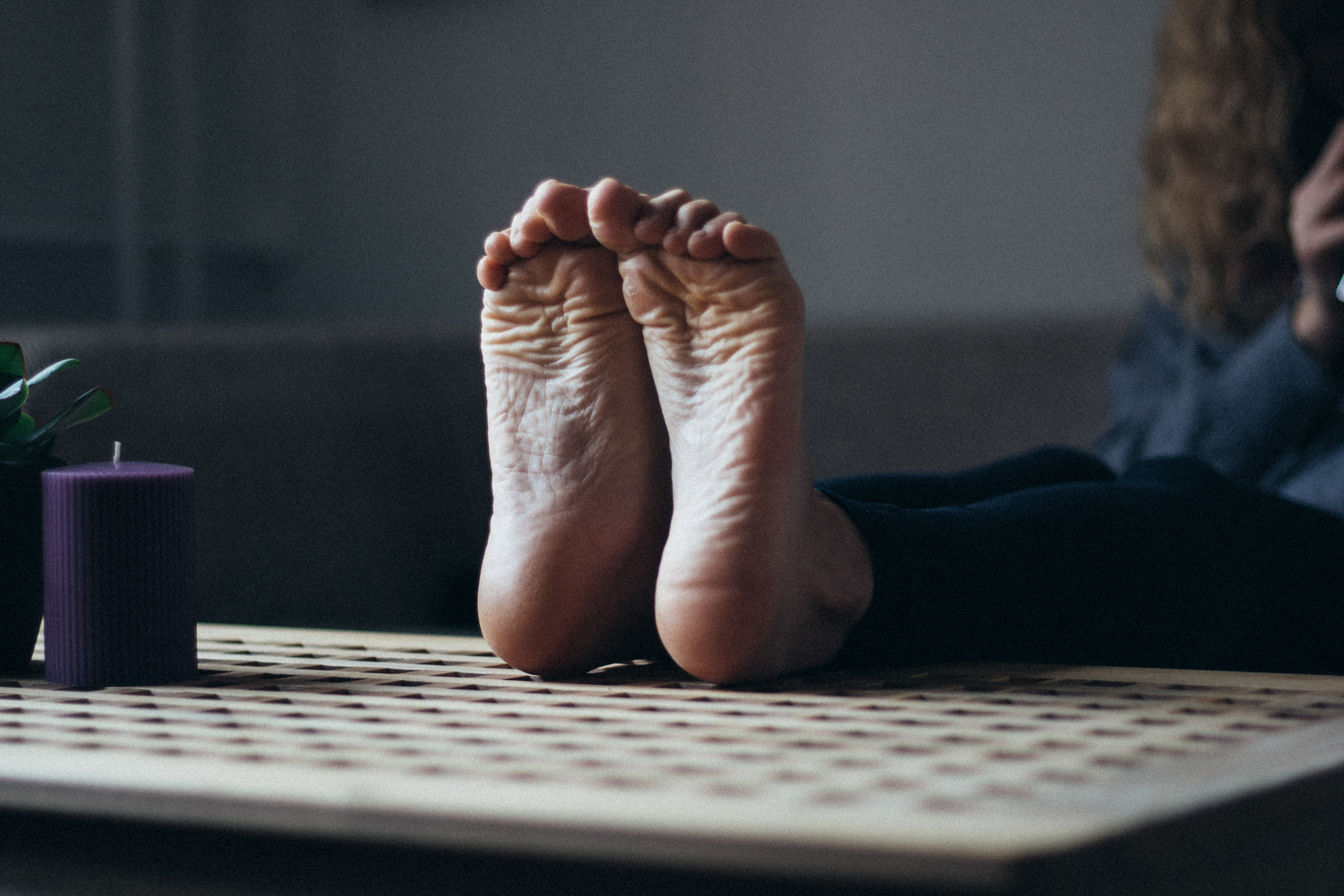 a woman's soles resting on a wooden coffee table with her toes scrunched