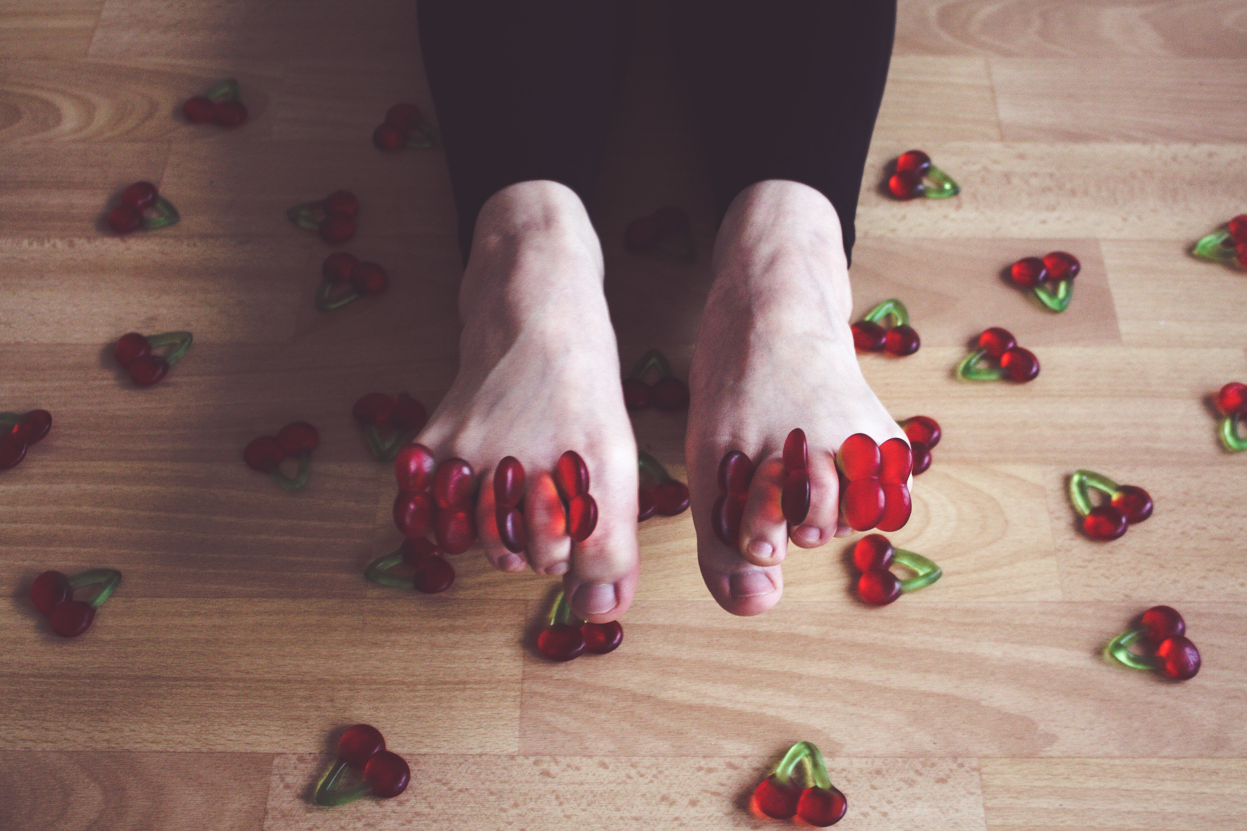 a woman with cherry shaped gummy candy between each toe
