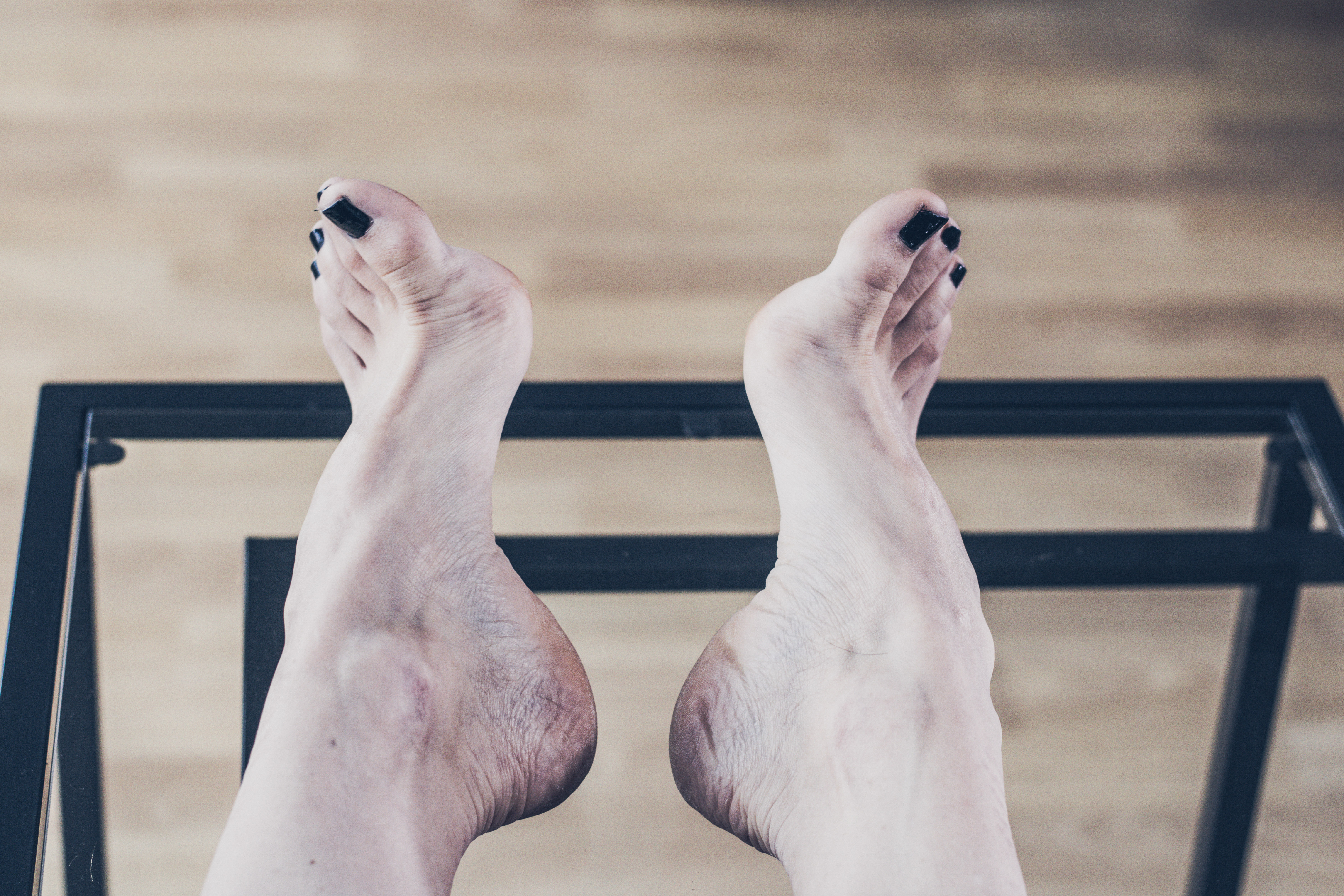 a woman's pale feet with black toenail polish 
