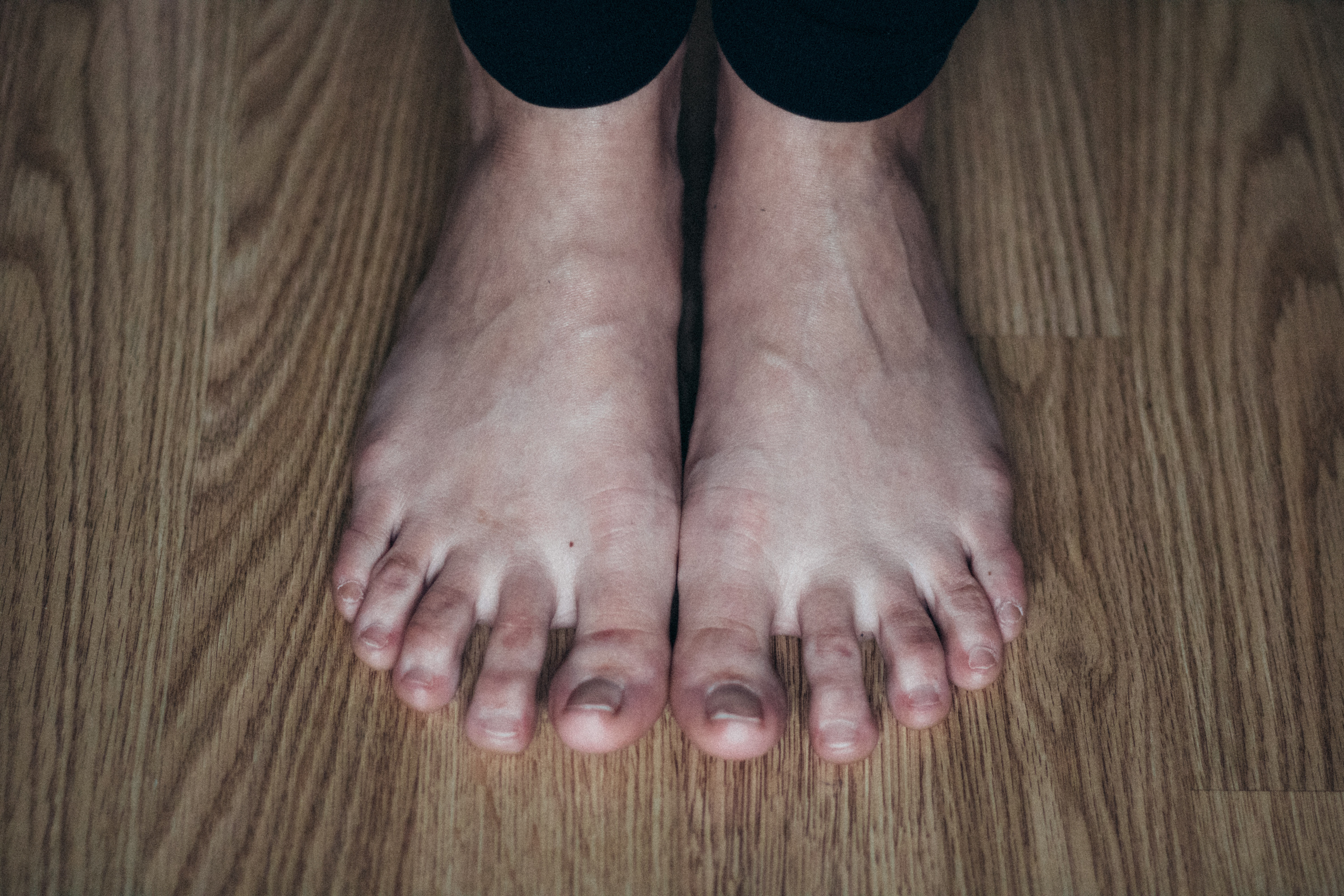 a woman's bare feet resting on a wood floor