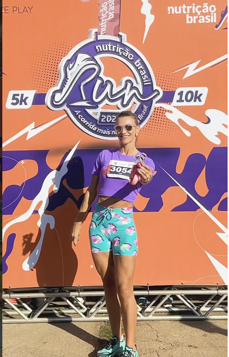 Corredora da NB Run com a medalha no painel oficial