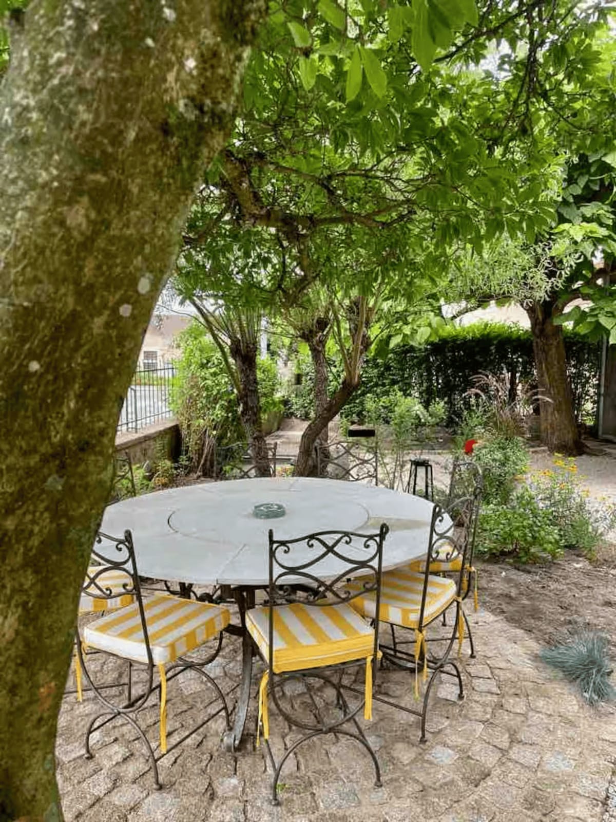 Terrasse avec table en fer forgé et chaises rayées jaunes
