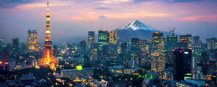 Tokyo skyline at twilight with illuminated Tokyo Tower and Mount Fuji visible in the distance under a colorful sky