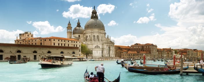 Gondolas floating on turquoise canal waters with Santa Maria della Salute basilica and historic Venetian buildings