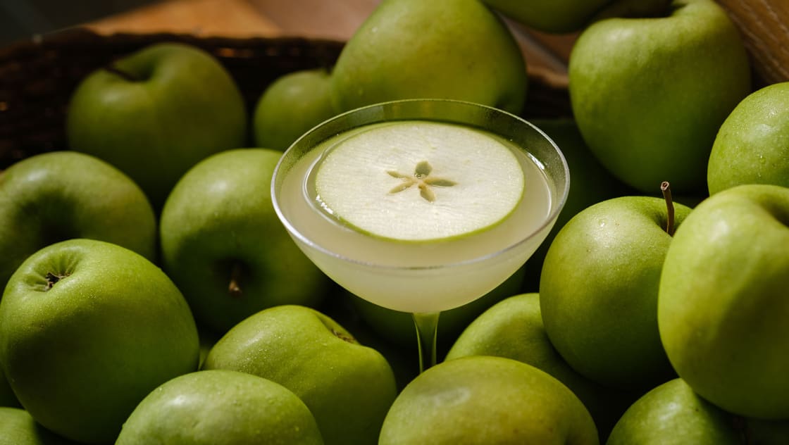 Ave's Applez cocktail surrounded by granny smith apples
