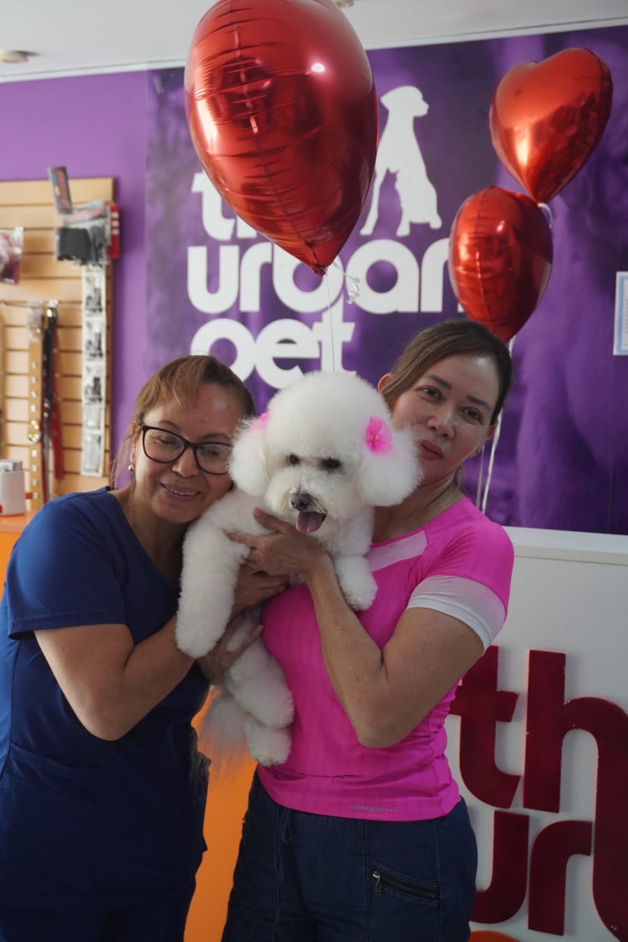 Clientas de The Urban Pet sosteniendo un caniche blanco en la tienda