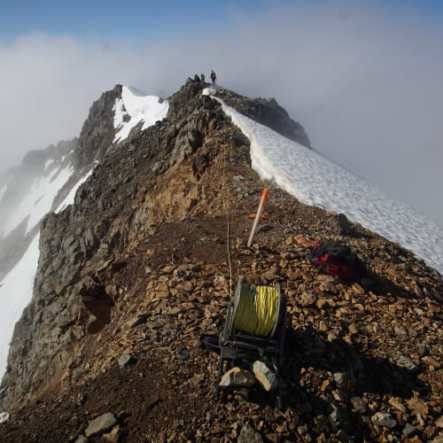 Crew laying IP survey wire along a narrow, rugged alpine ridge