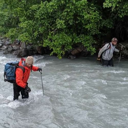 Field crew navigating a fast-moving stream during soil sampling program