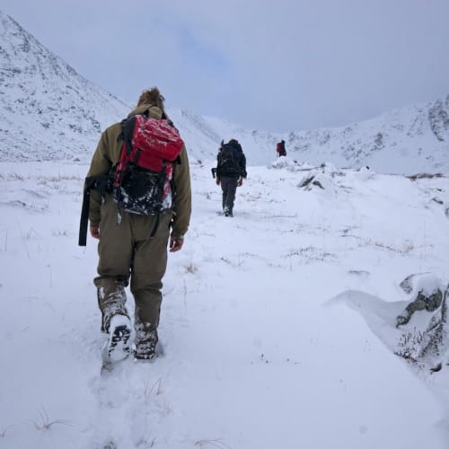 Field crew trekking through September snow to reach geophysics survey line